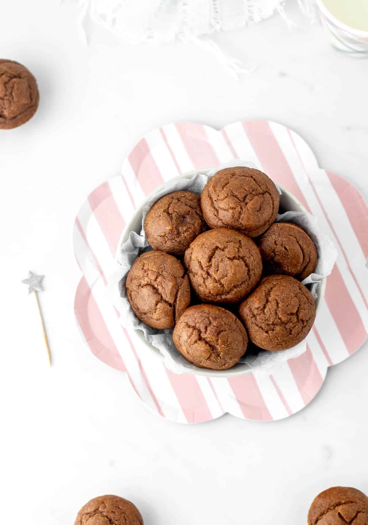 Date muffins stacked on top of one another in a white bowl on top of a decorative plate.