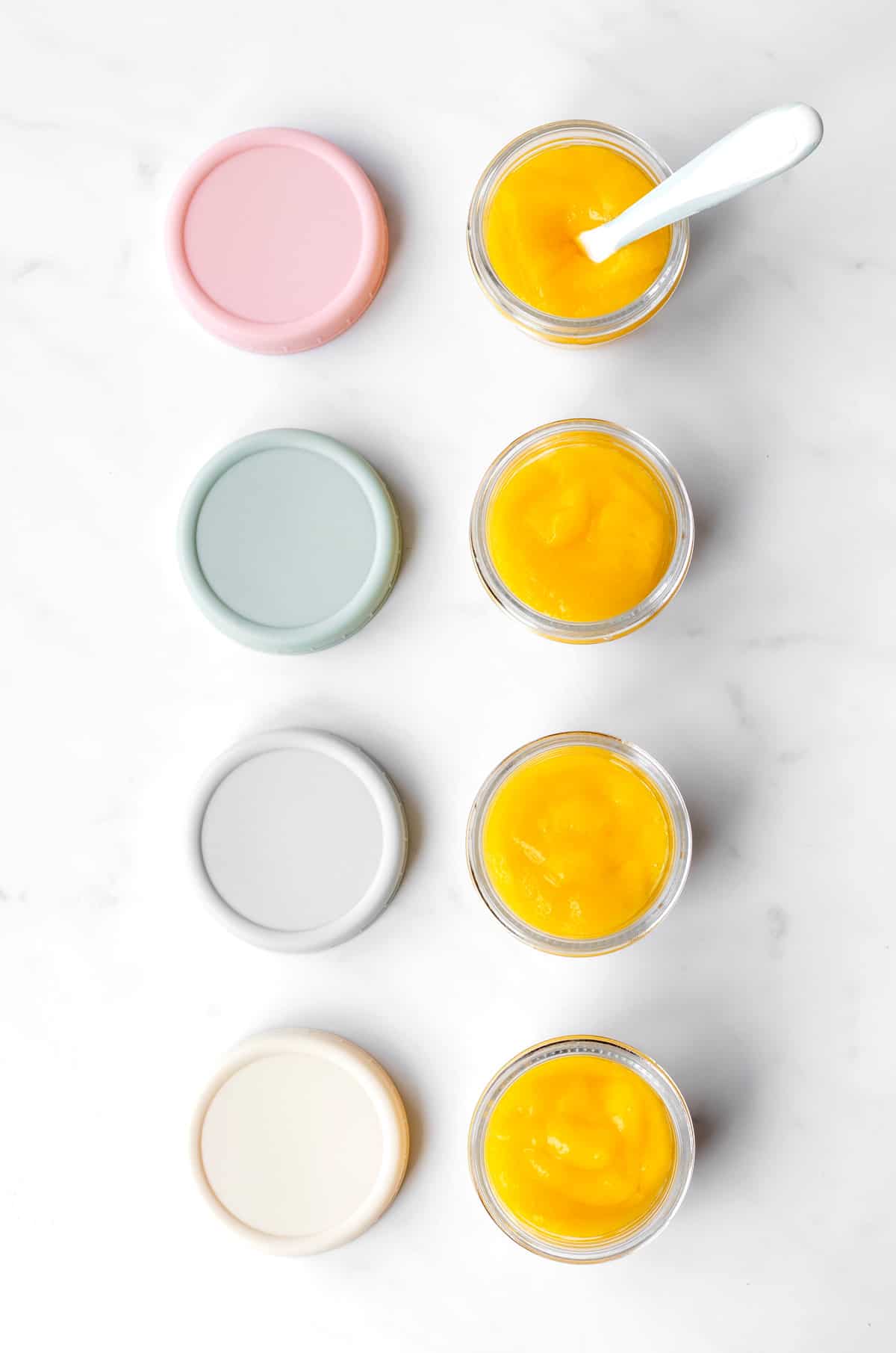 Small glass jars lined up next to each other of mango puree.