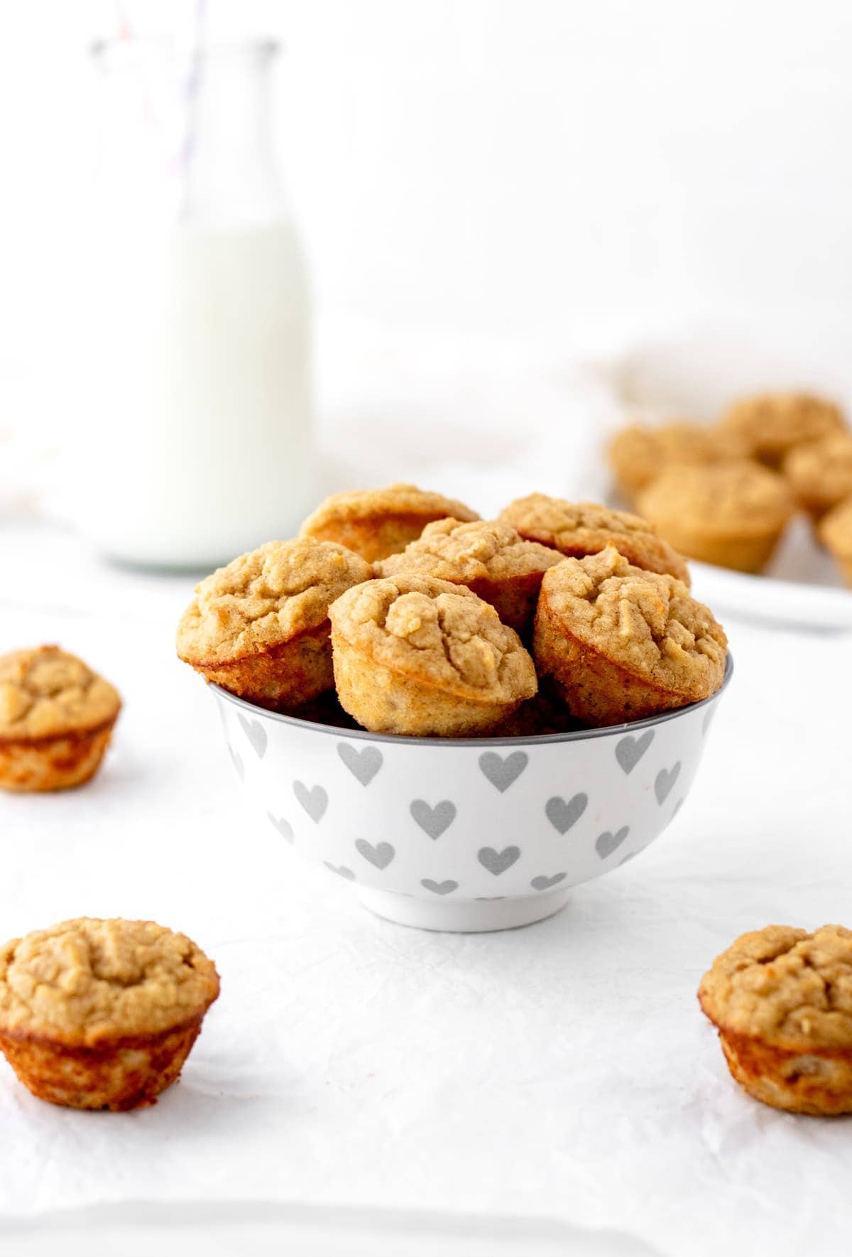 Banana bread muffins stacked on top of one another in a heart decorated bowl on the counter.