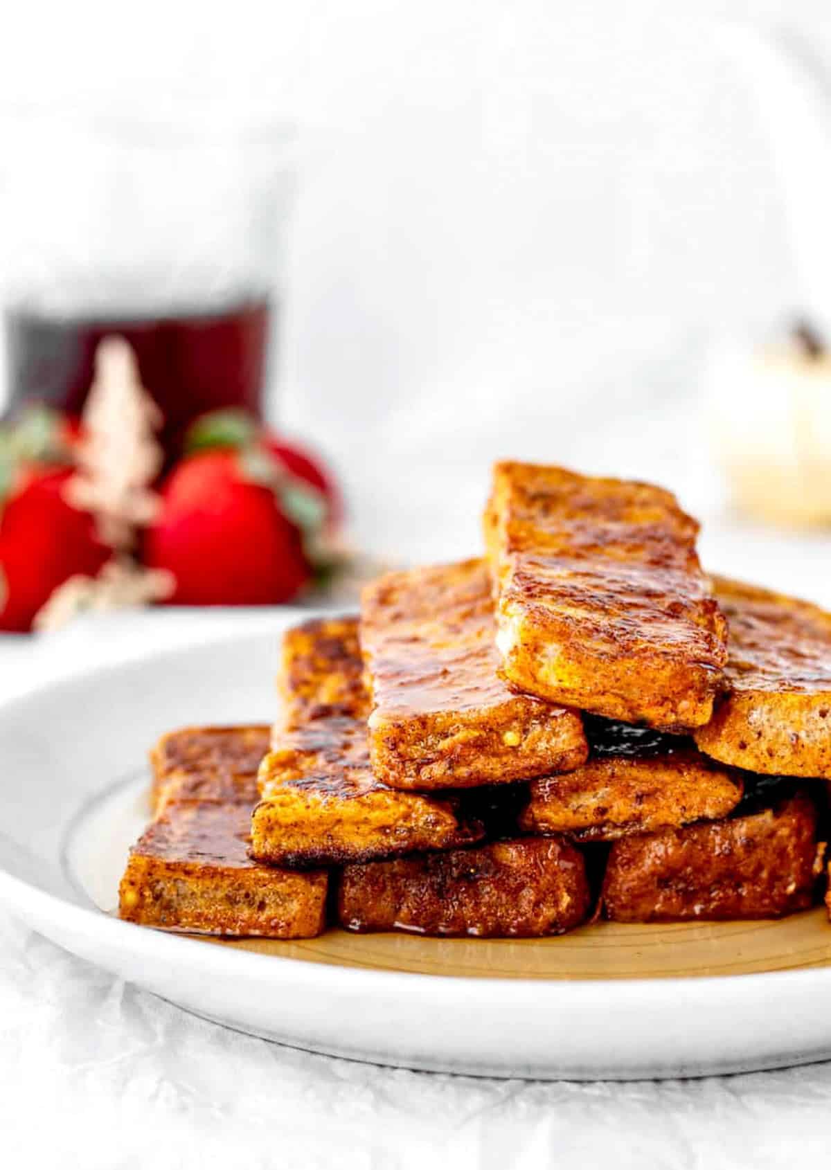 Pumpkin French toast sticks stacked on a plate with syrup on them.