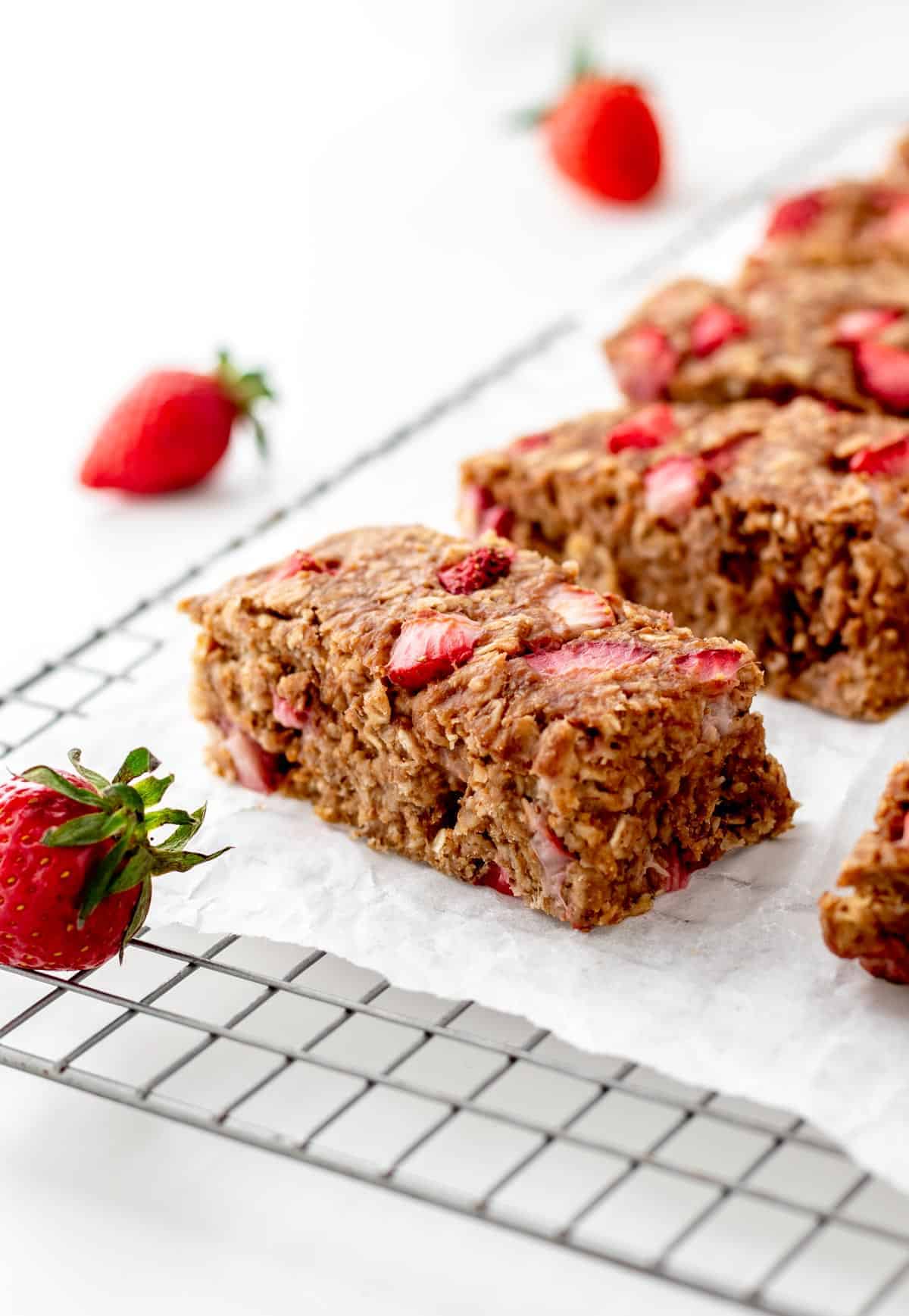 Strawberry banana oat bars lined up next to each other on a cooling rack.