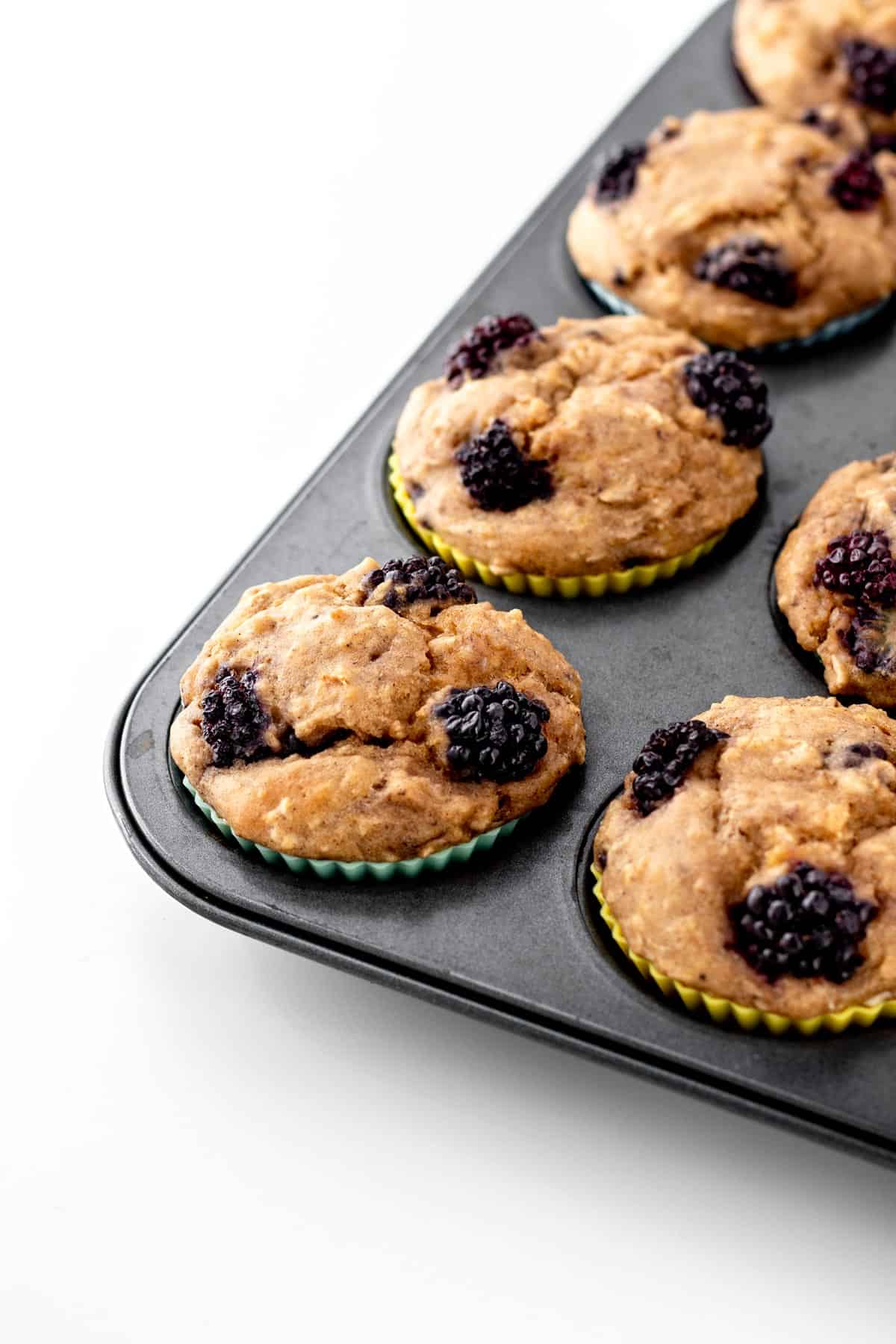 Four banana blackberry oatmeal muffins in the muffin tin after baking.