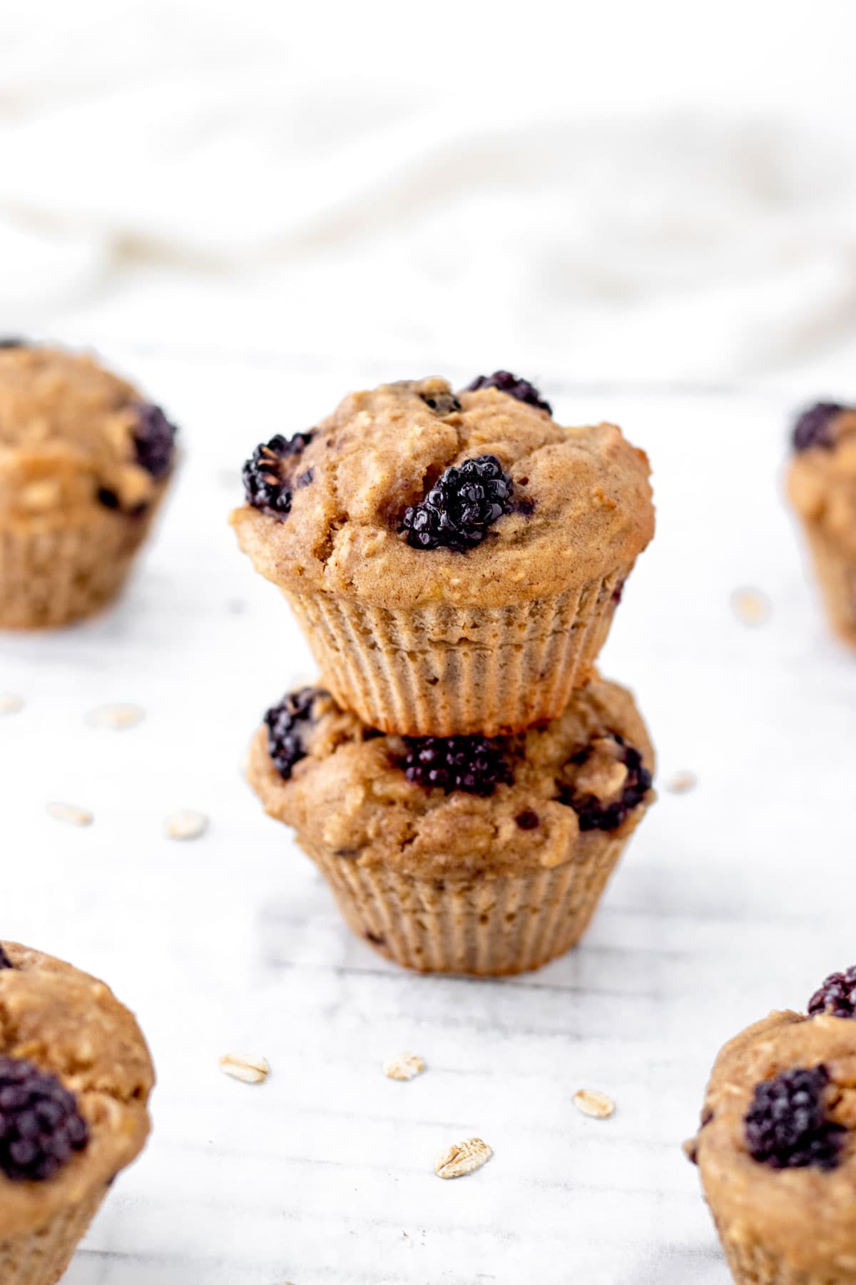 Two banana blackberry muffins with oats stacked on top of each other.
