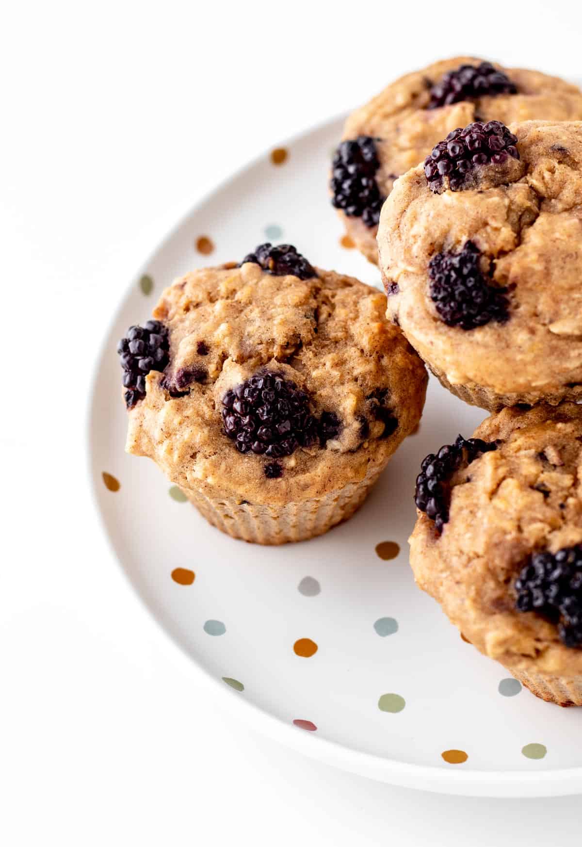 Blackberry muffins with yogurt on a colorful polka dotted plate.