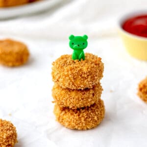 Three cauliflower chicken nuggets stacked on top of each other with a teddy bear pick poked in the top.