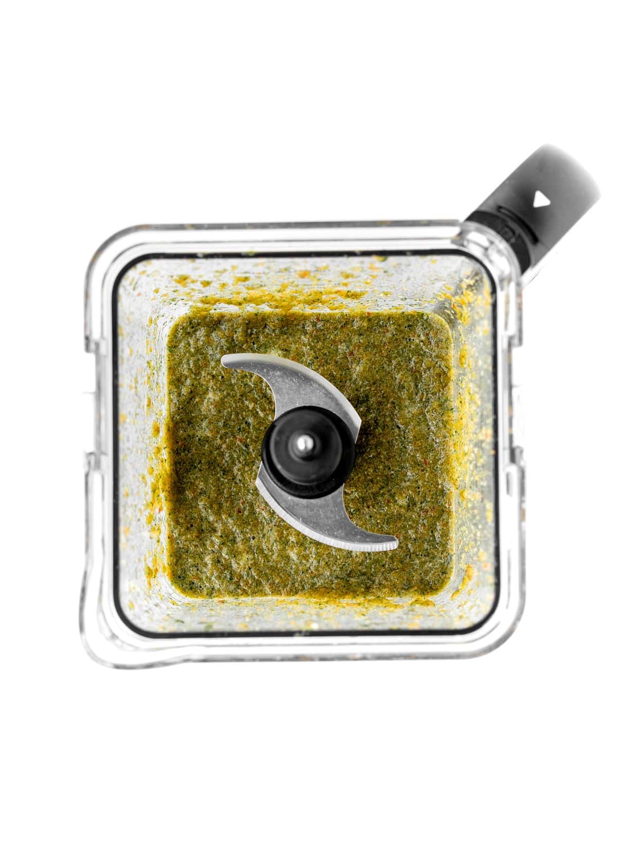 Vegetables blended up in a blender to form a green sauce.