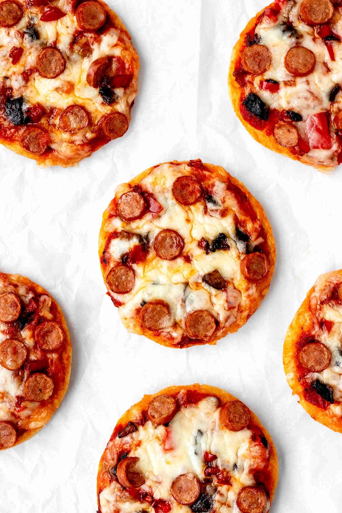 A birds-eye view of mini pizzas on a counter.