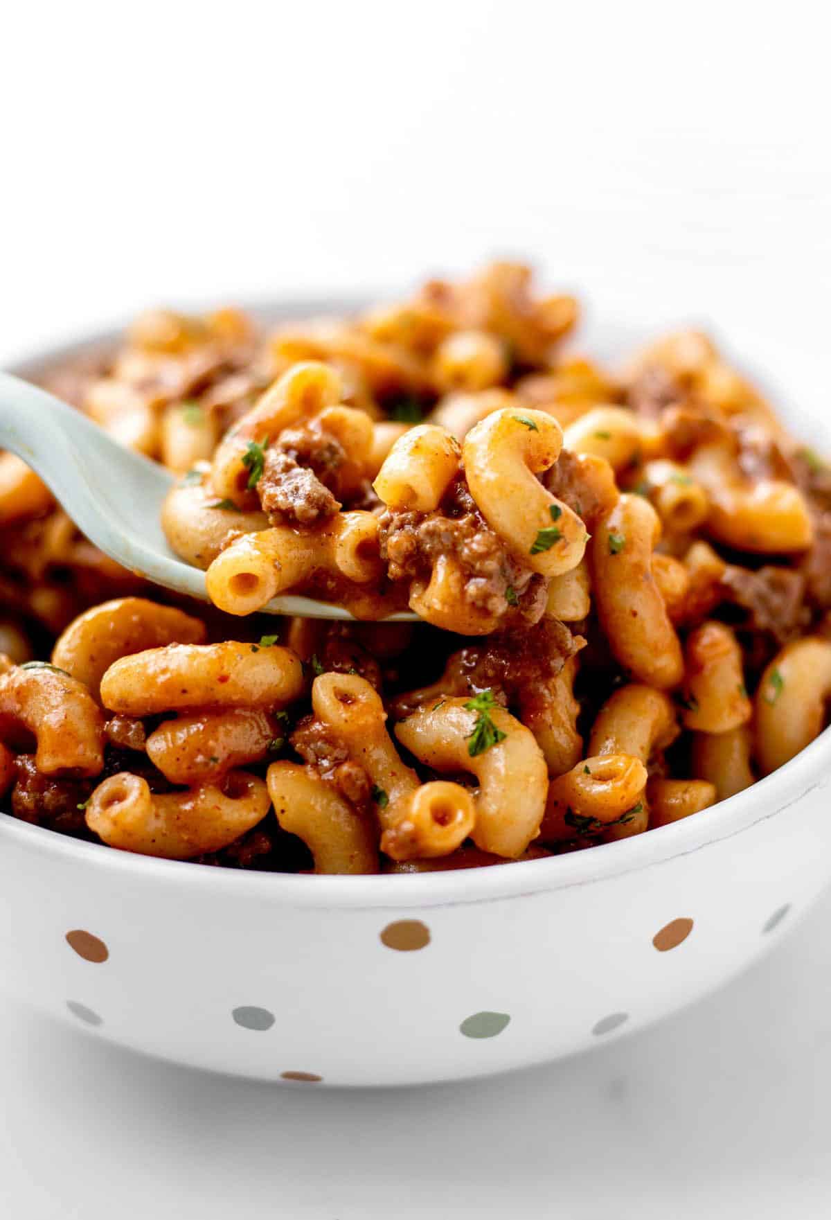 Homemade hamburger helper in a white polka dot bowl with a fork in it.