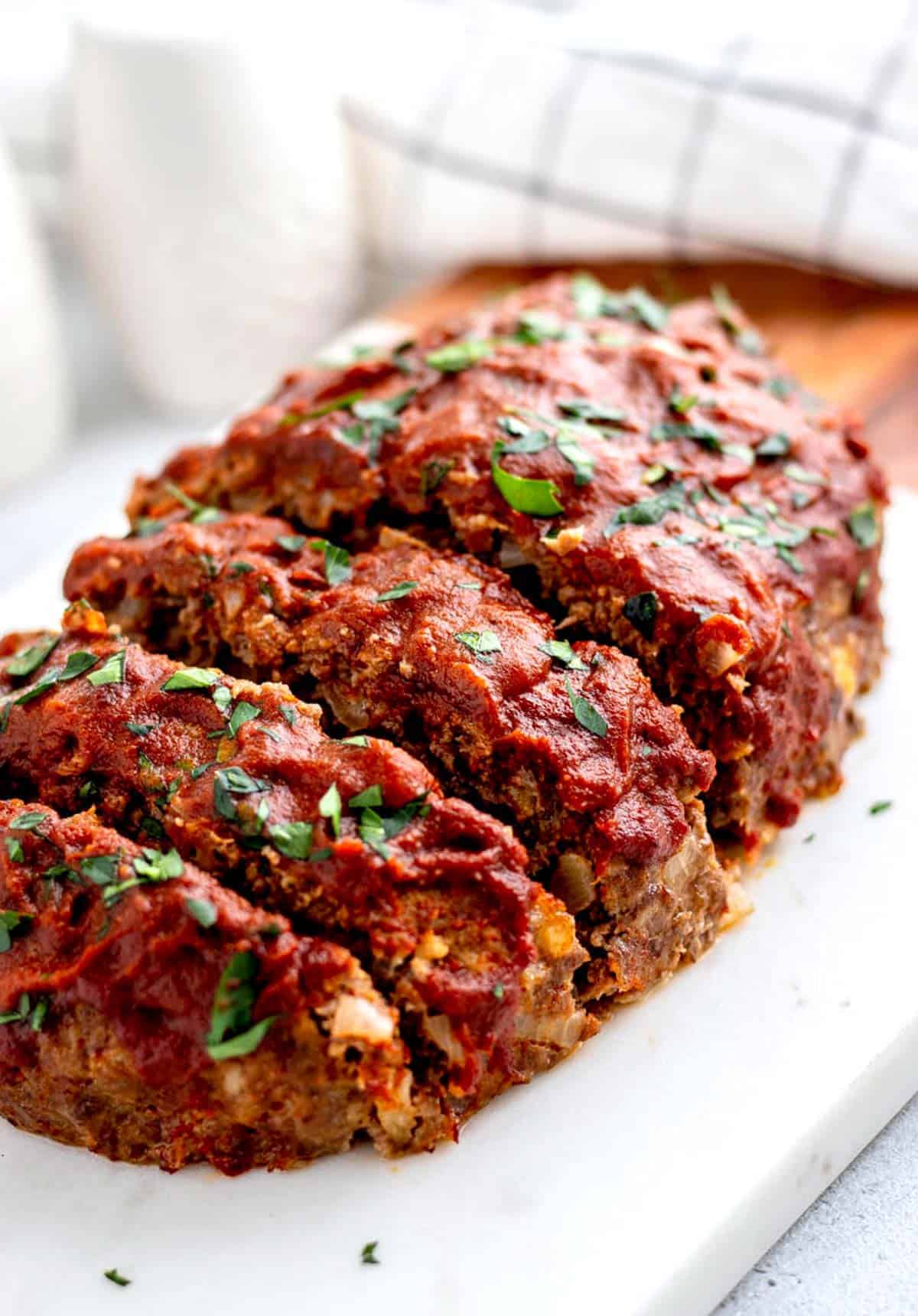 5-ingredient meatloaf with slices cut into it. on a white platter.