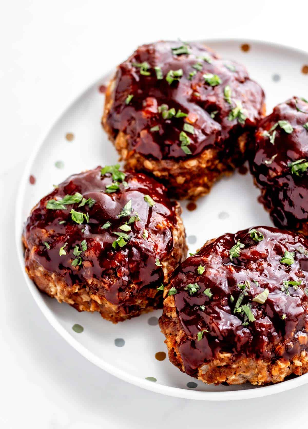 Mini meatloaf muffins next to one another on a polka dot plate.