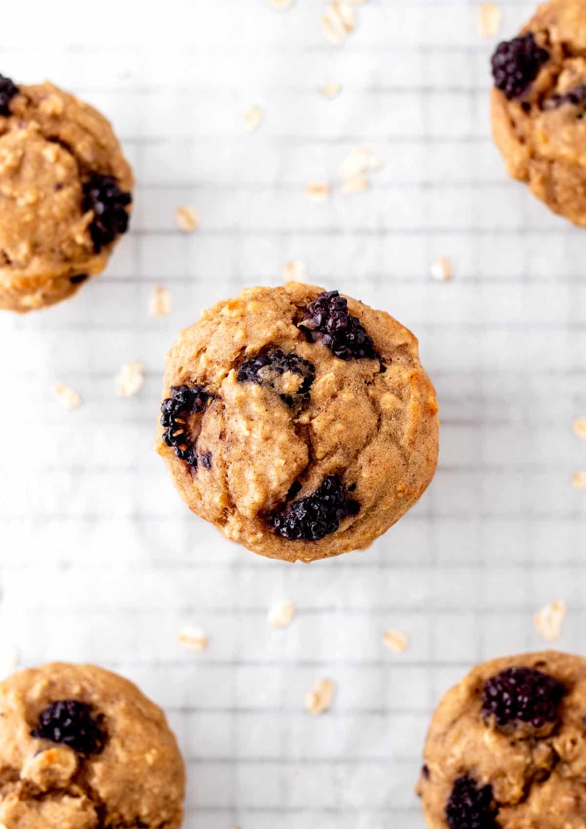 A birds-eye view of the healthy blackberry muffins spread out on a cooling rack lined with parchment paper.