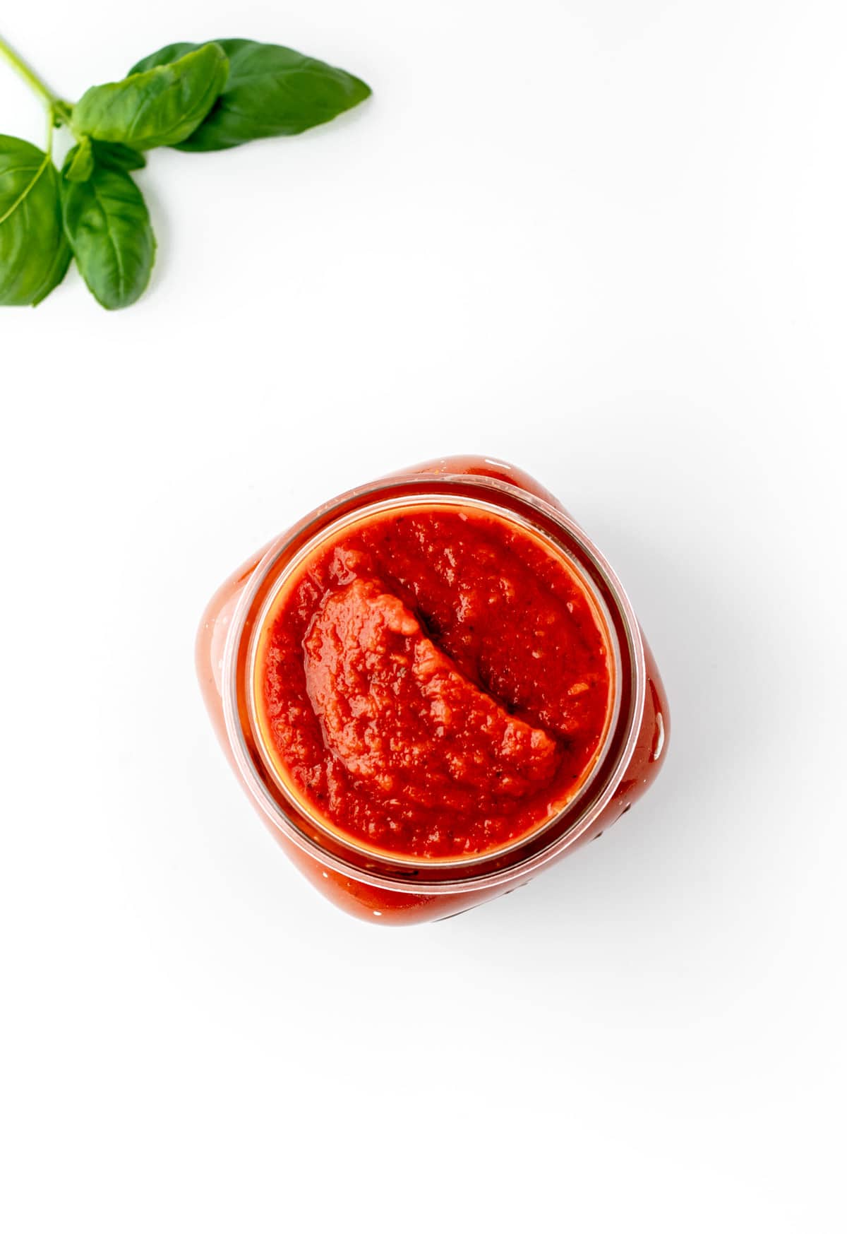 A clear glass jar of healthy pasta sauce for kids.