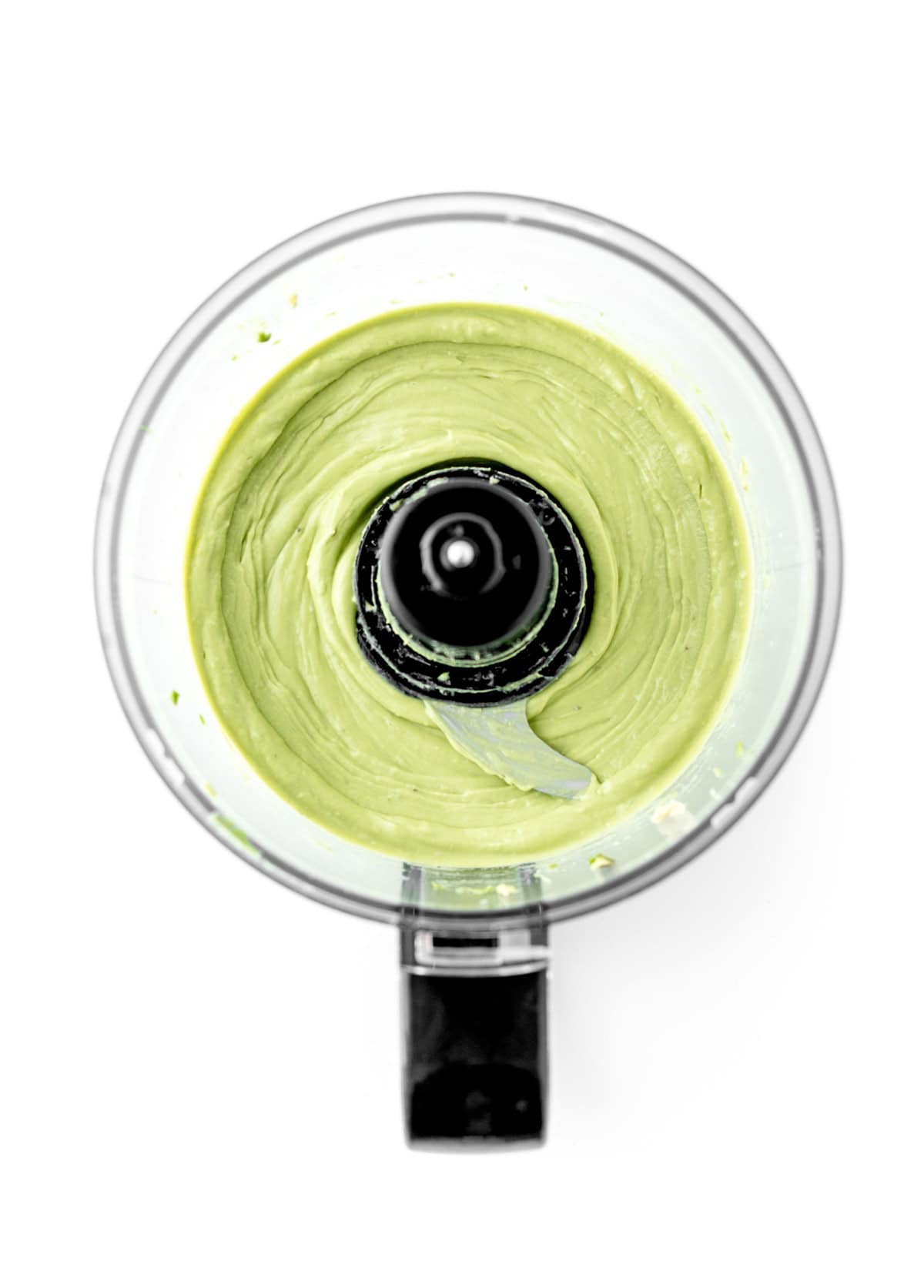 Blending the avocados in a food processor until smooth and creamy.