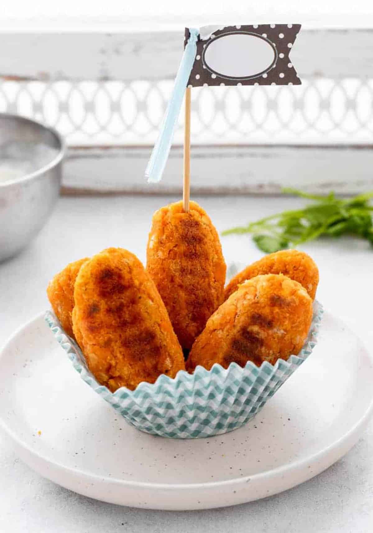 Sweet potato tots in a blue checkered paper cup with a little flag poked into the top of one.