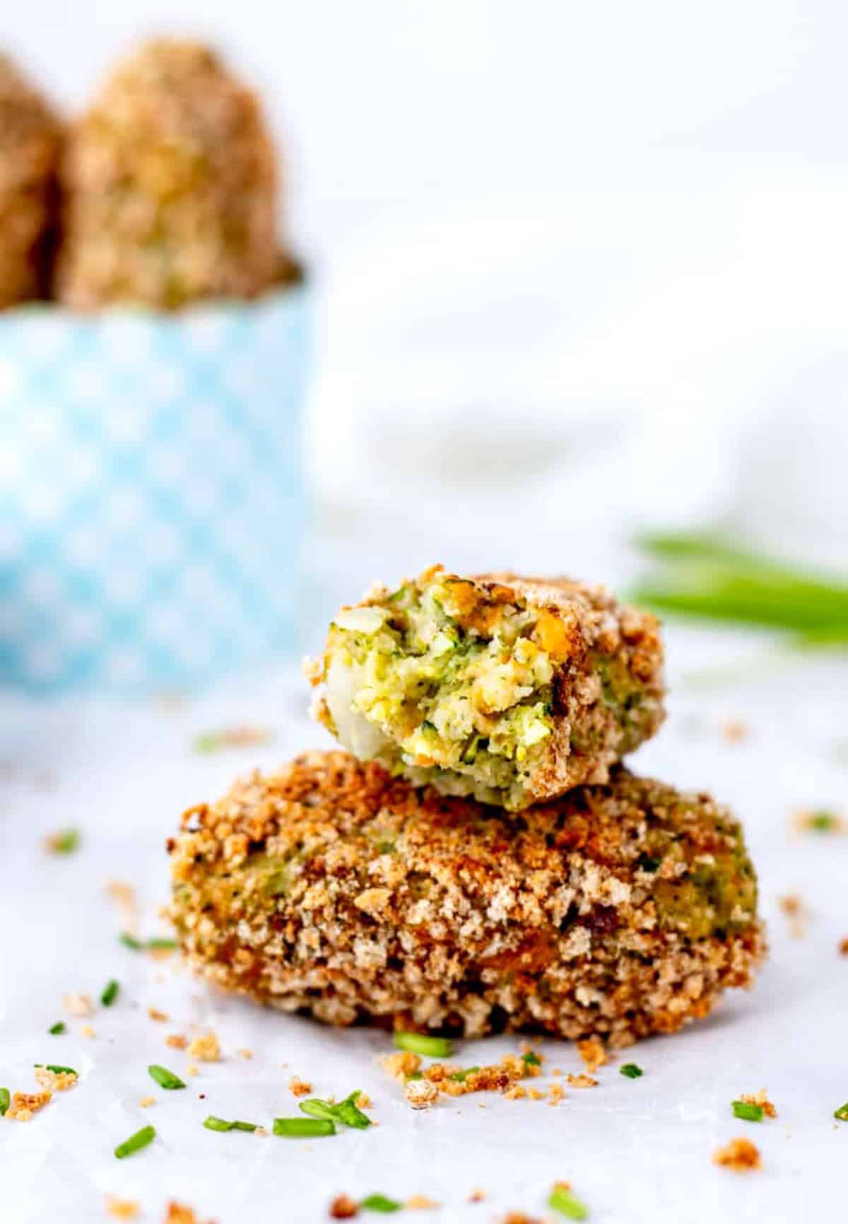 Broccoli cheese tots stacked on top of each other with a bite taken out of one.