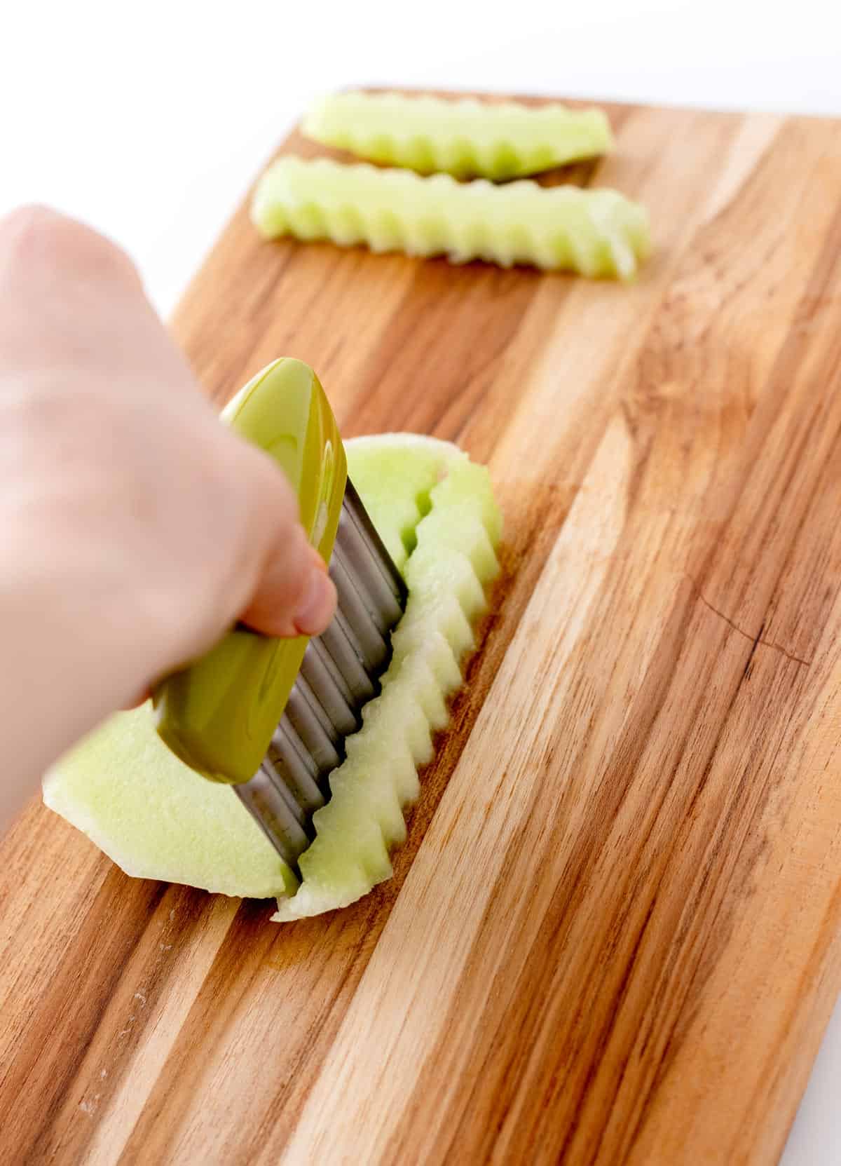 Using a crinkle cutter to make fries out of honeydew melon.