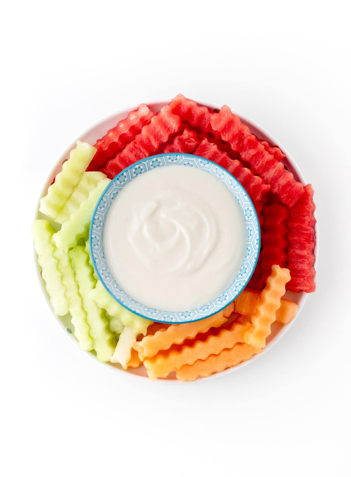 Fruit fries on a platter with a bowl of fruit dip in the middle.