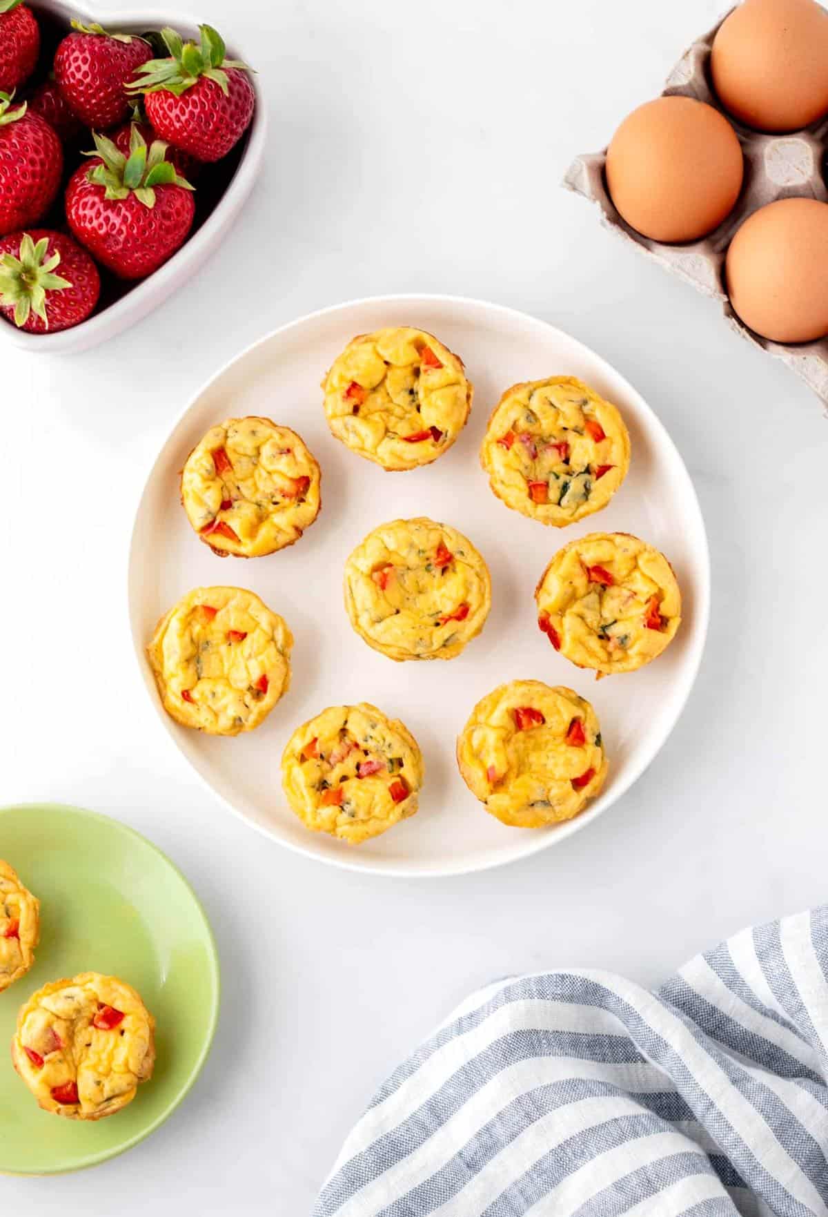 Mini egg bites with cottage cheese and veggies on a white plate on the table.