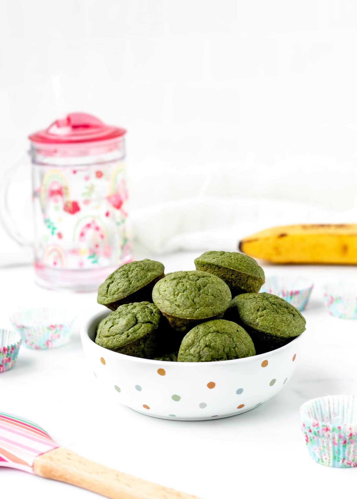 Green monster muffins in a polka dot bowl on a dining table.