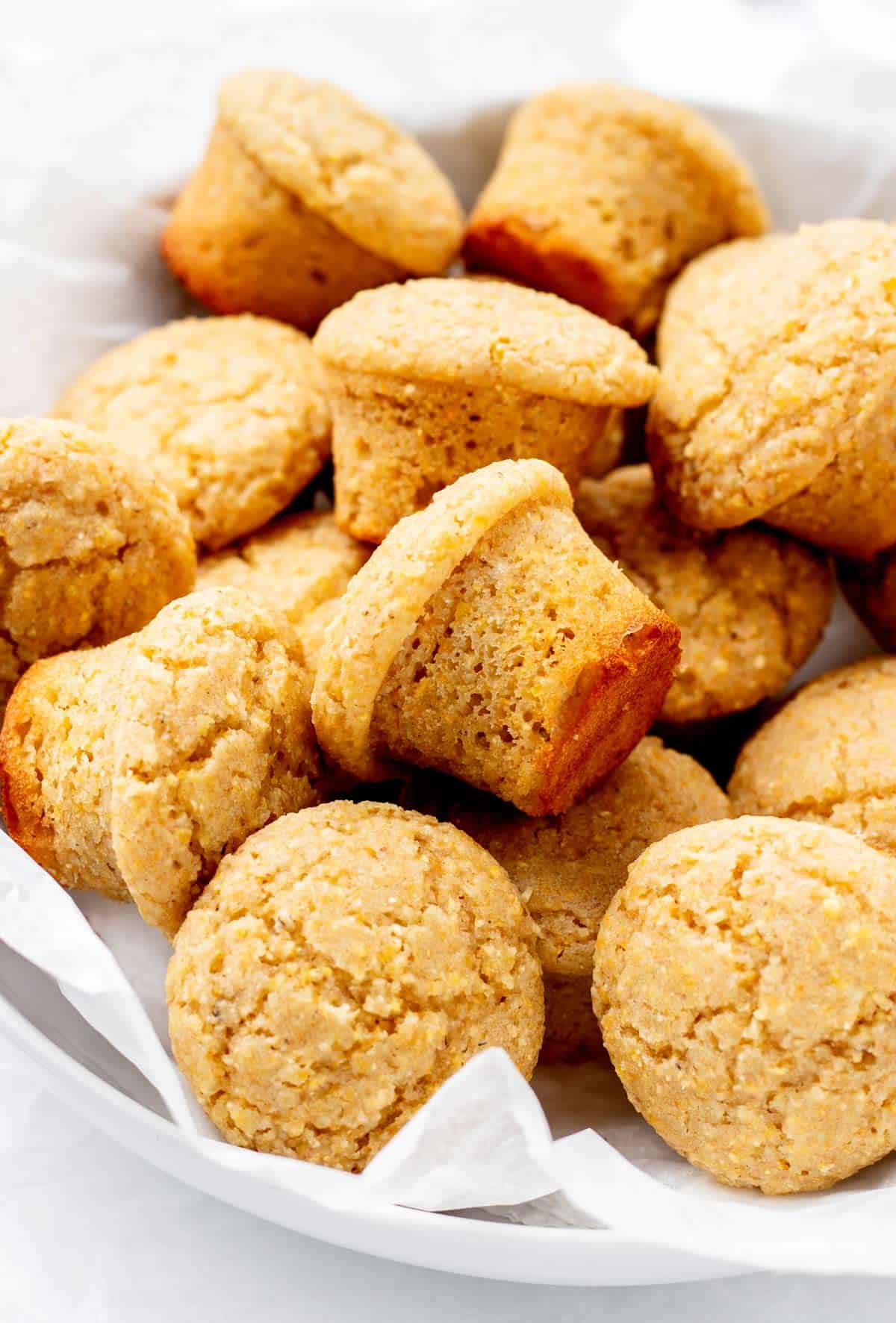 Mini cornbread muffins stacked on top of each other in a bowl.