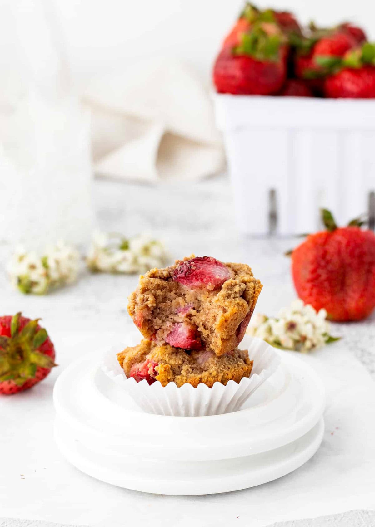 A half-bitten mini strawberry muffin on top of another muffin on a small plate.