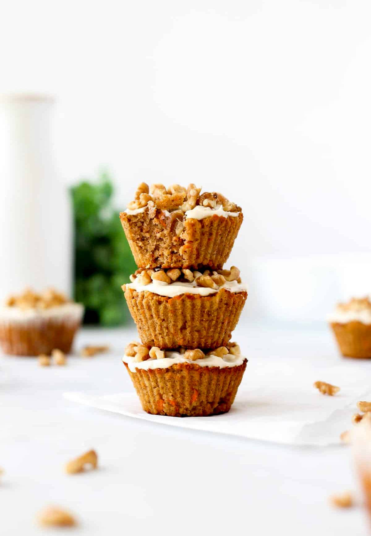 3 carrot pineapple muffins stacked on top of one another with the top one with a bite taken out of it.