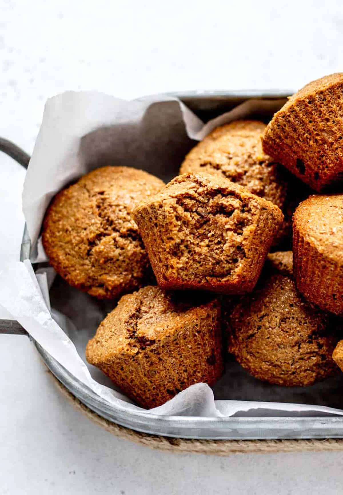 Honey bran muffins in a tray with a bite taken out of one.