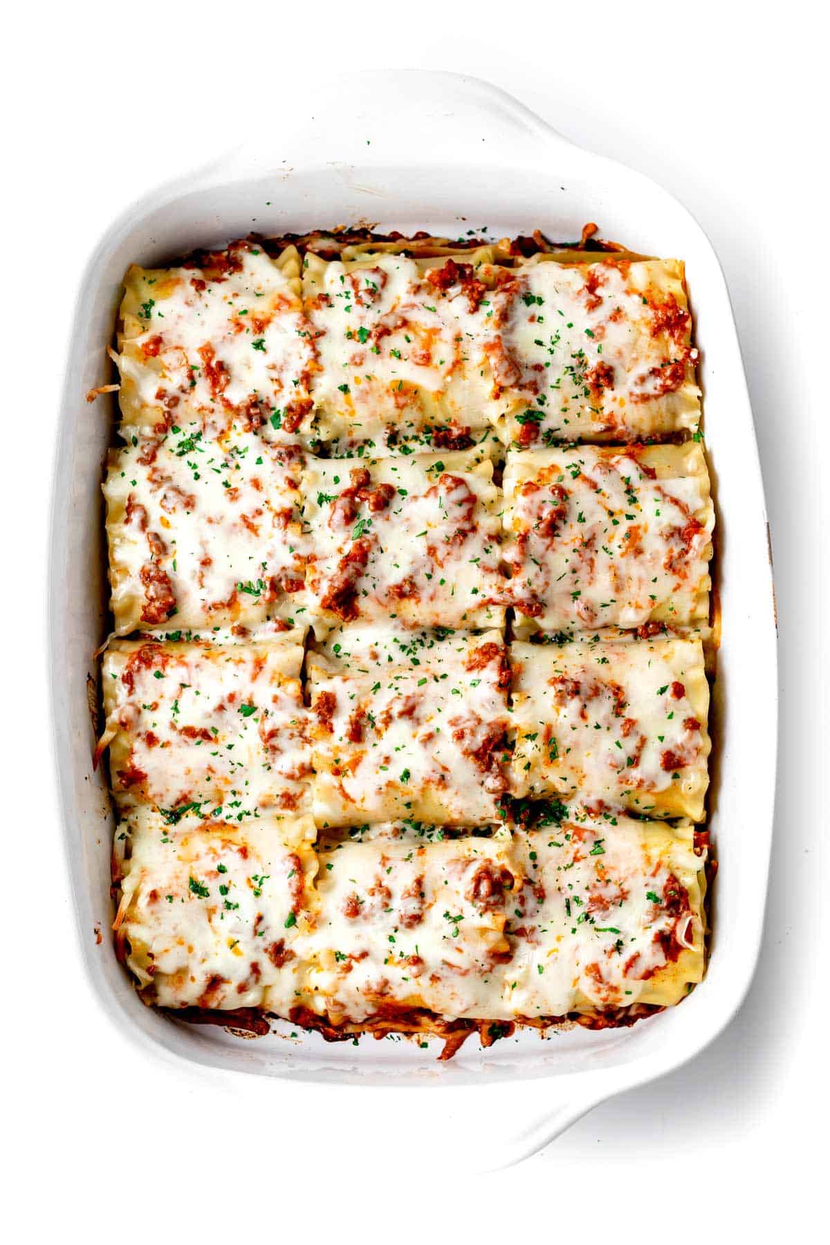 A birds-eye view of lasagna roll-ups with cottage cheese in a baking dish, right out of the oven.