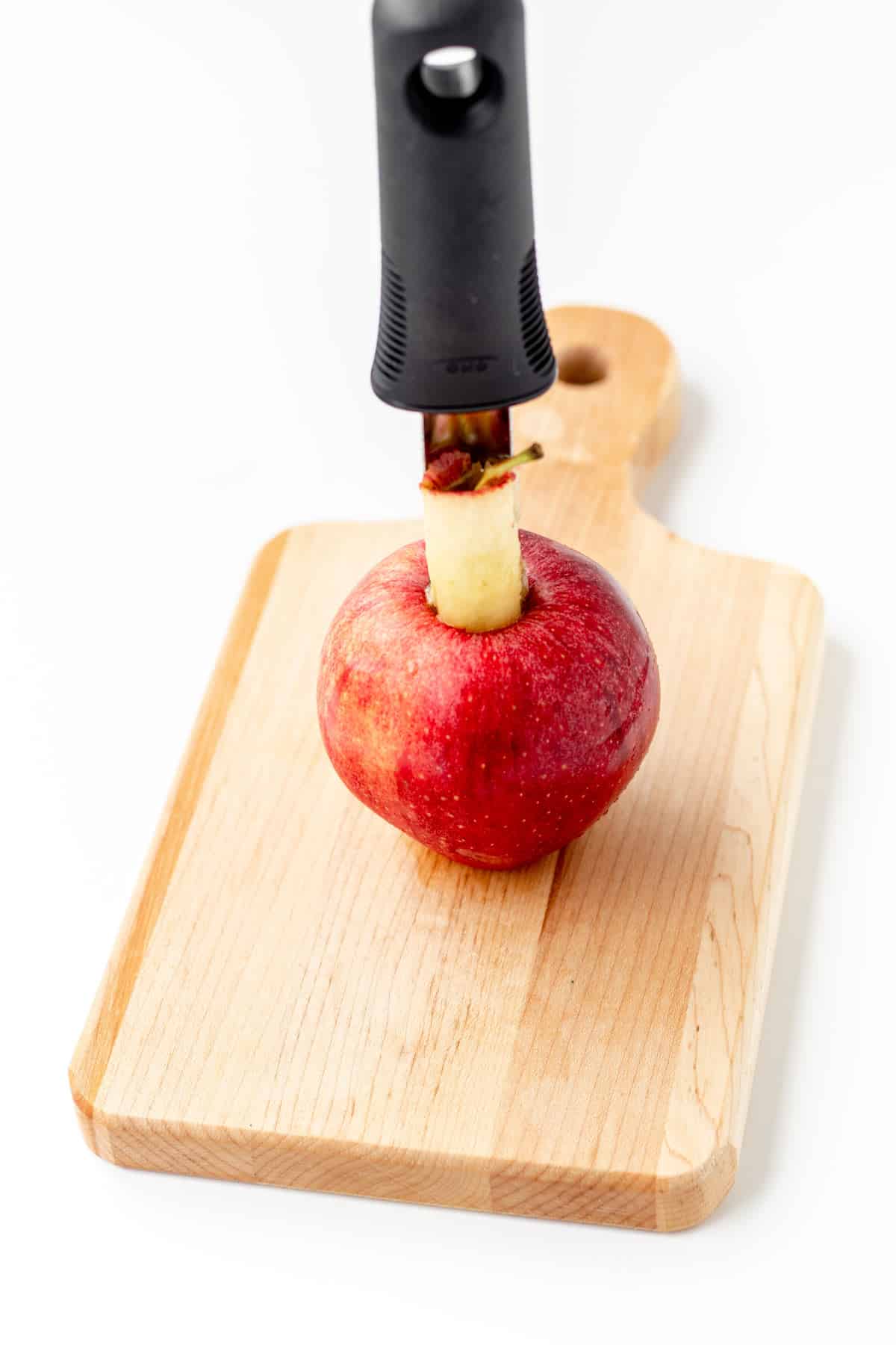 Coring an apple for the apple slice cookies on a cutting board.