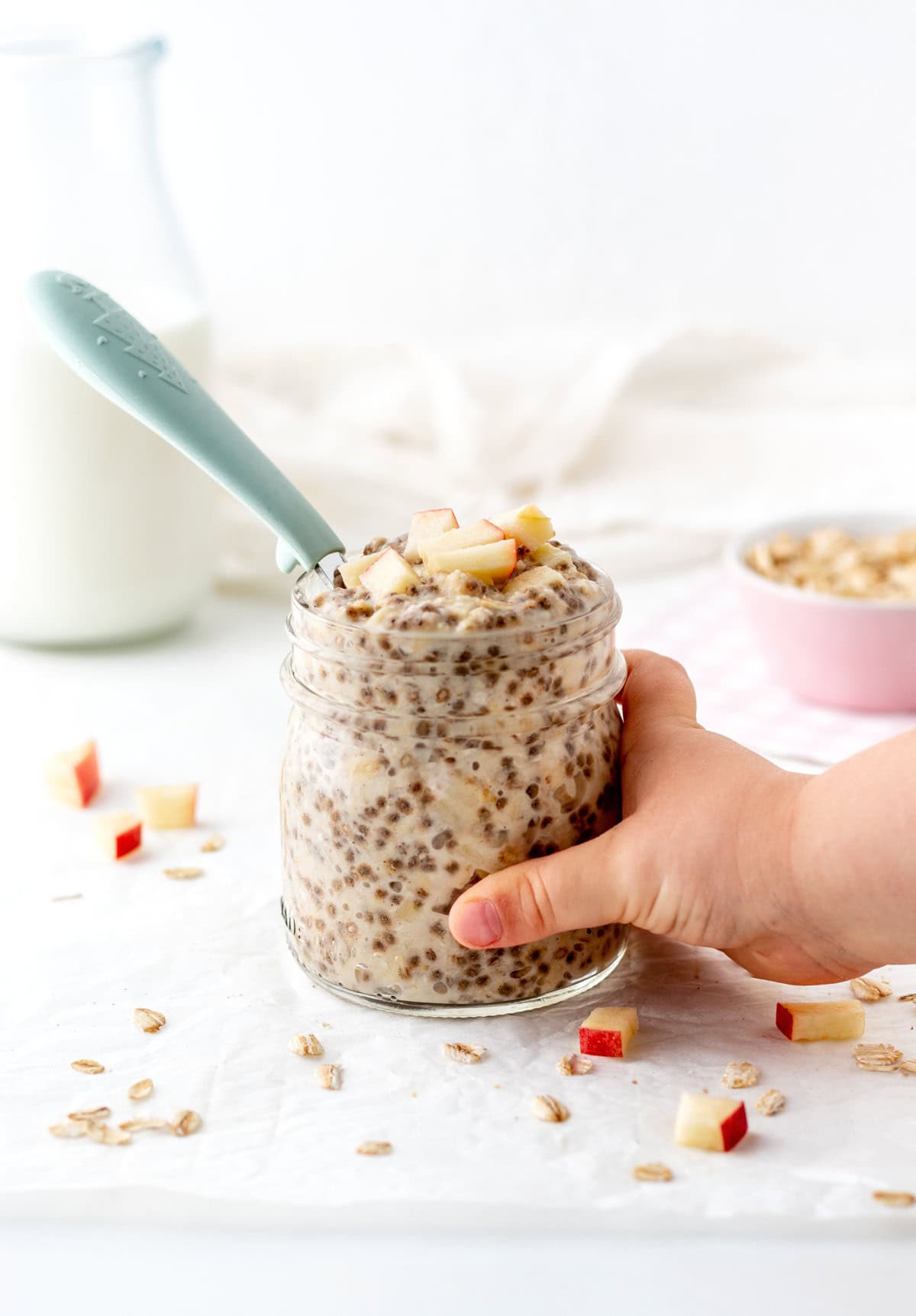 A small jar of applesauce overnight oatmeal being held in a child's hand.