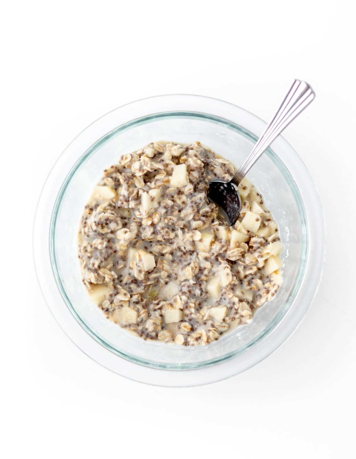 Stirring together the applesauce overnight oats mixture in a glass bowl.