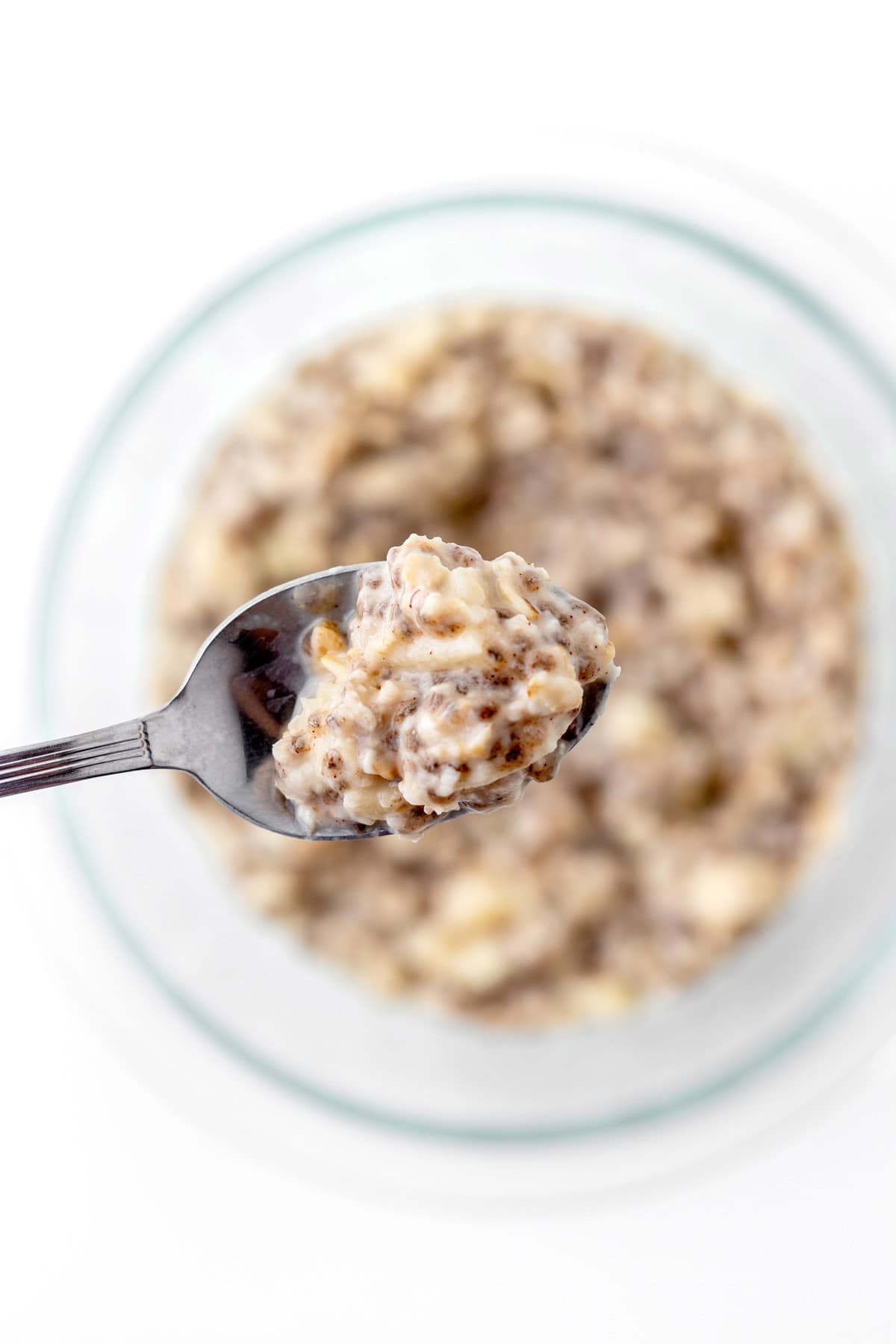 A spoonful of overnight oats with a bowl of oats in the background.