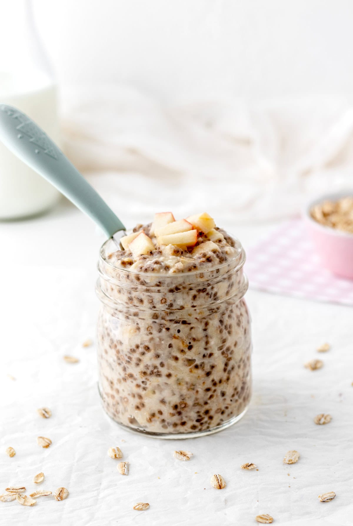 Applesauce overnight oats in a jar with a spoon in it.