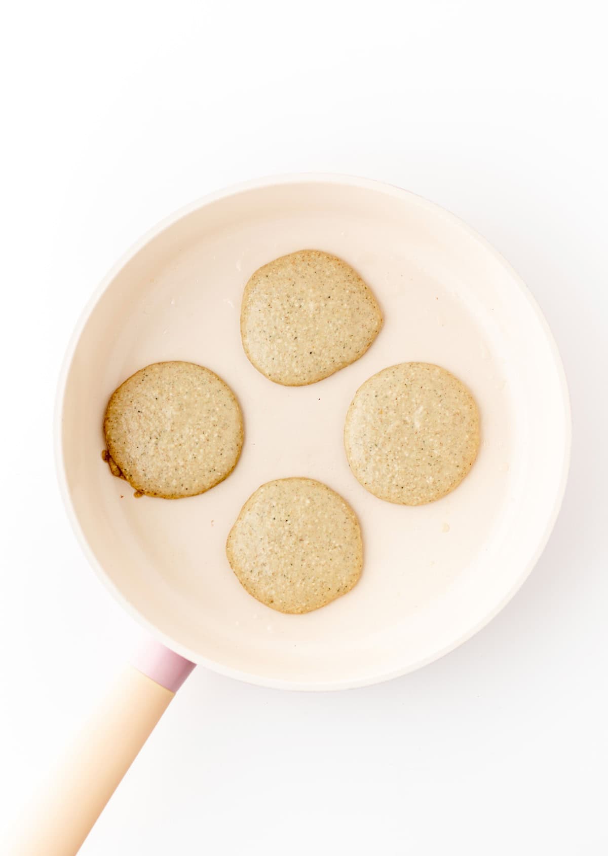 4 banana zucchini pancakes cooking in a pan.