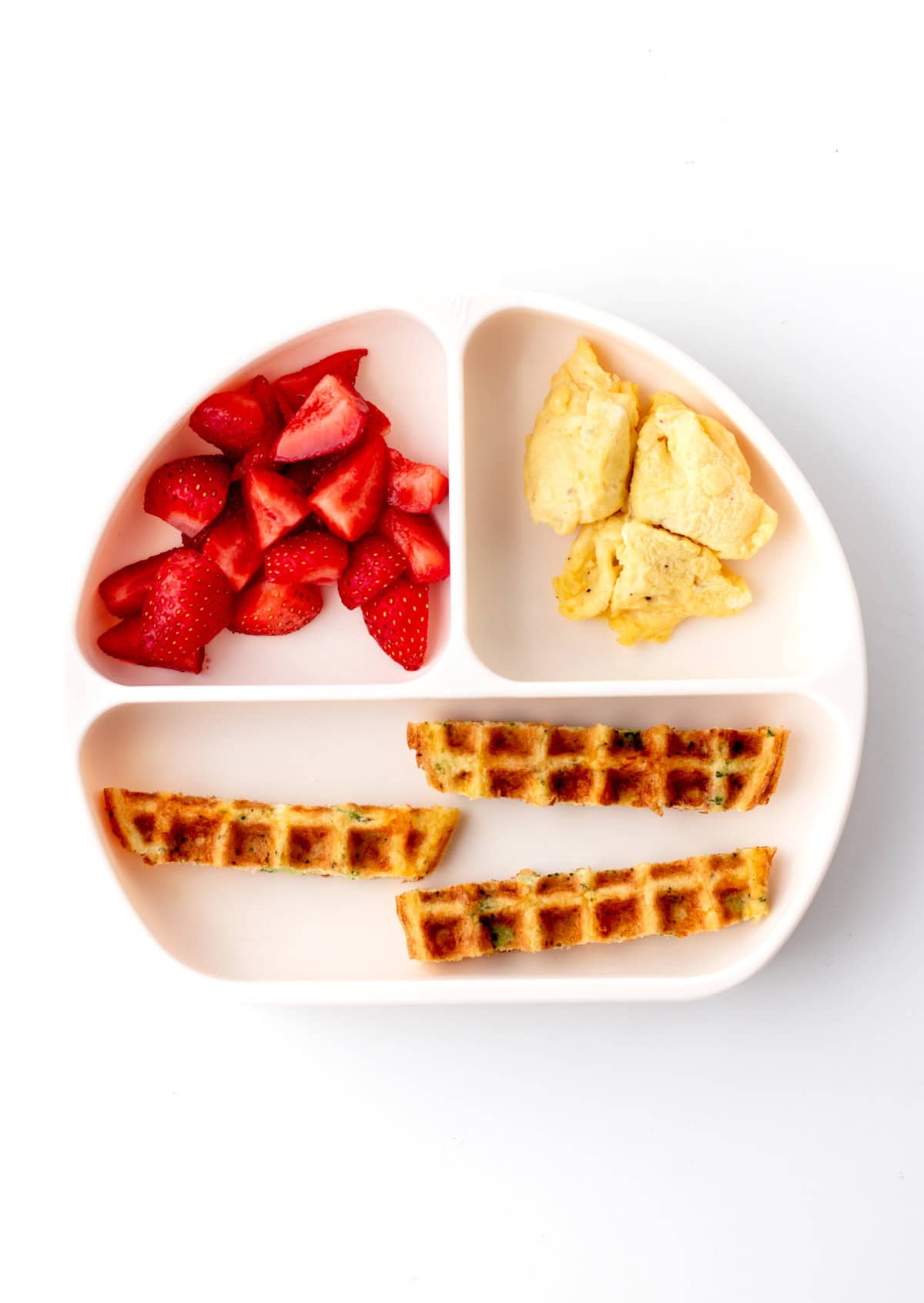 A divide plate with strips of broccoli cheese waffles and berries.