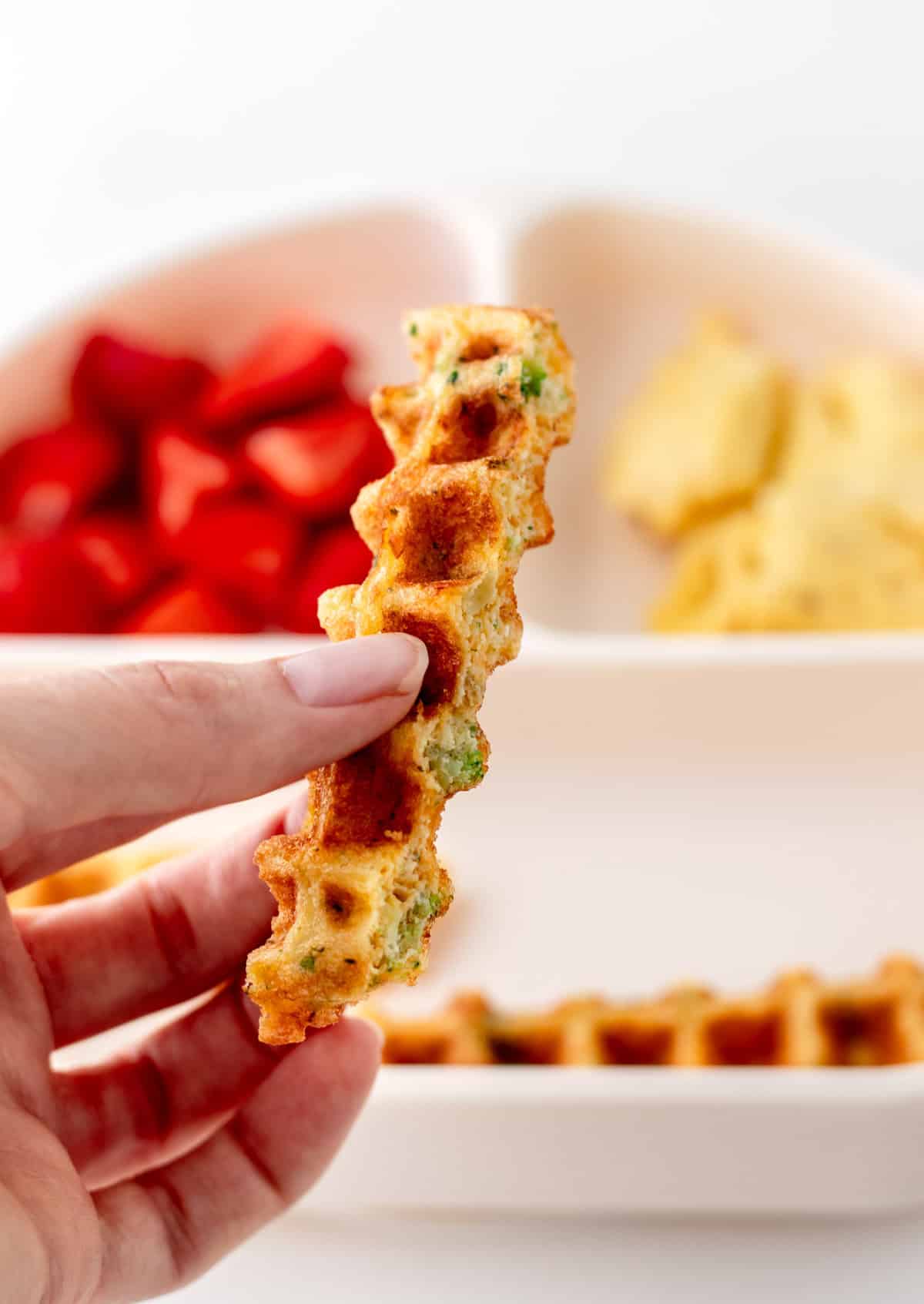 A finger-like strip of a broccoli cheese waffle.