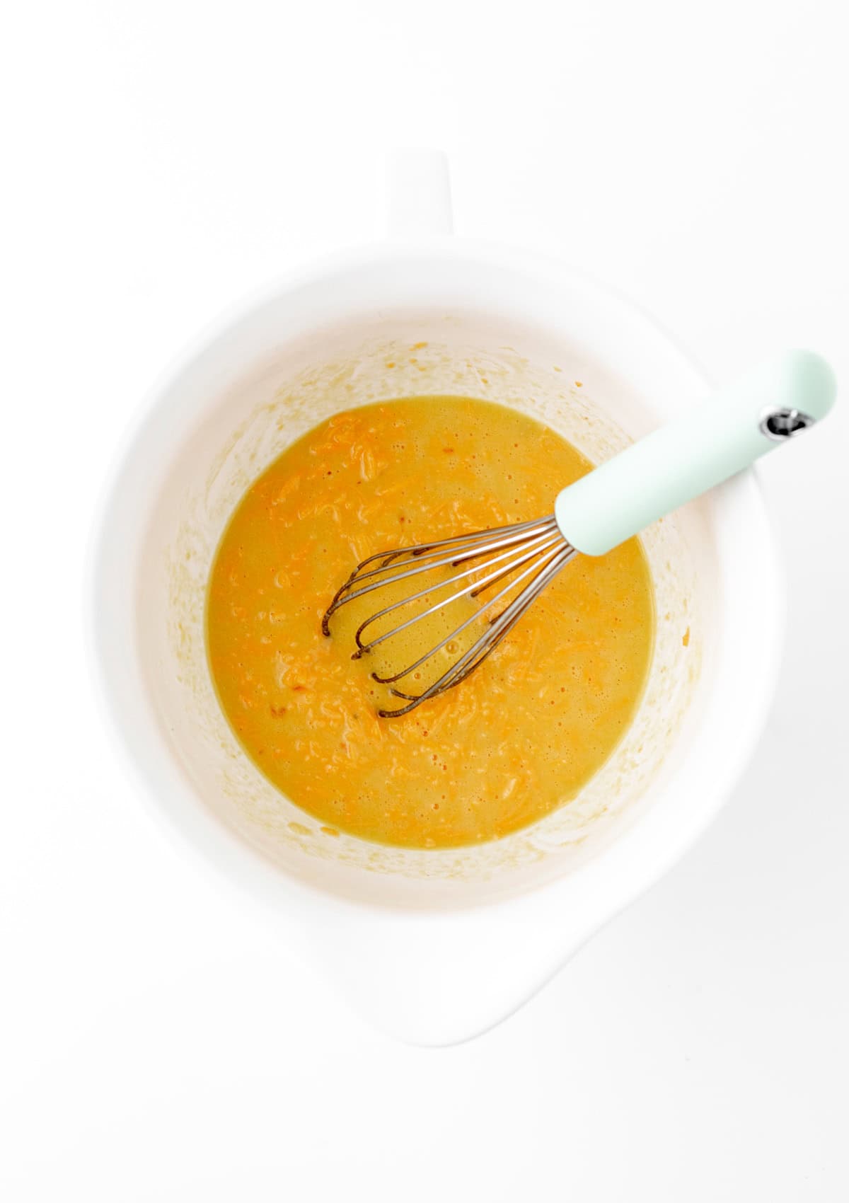 Whisking together eggs in a mixed bowl.