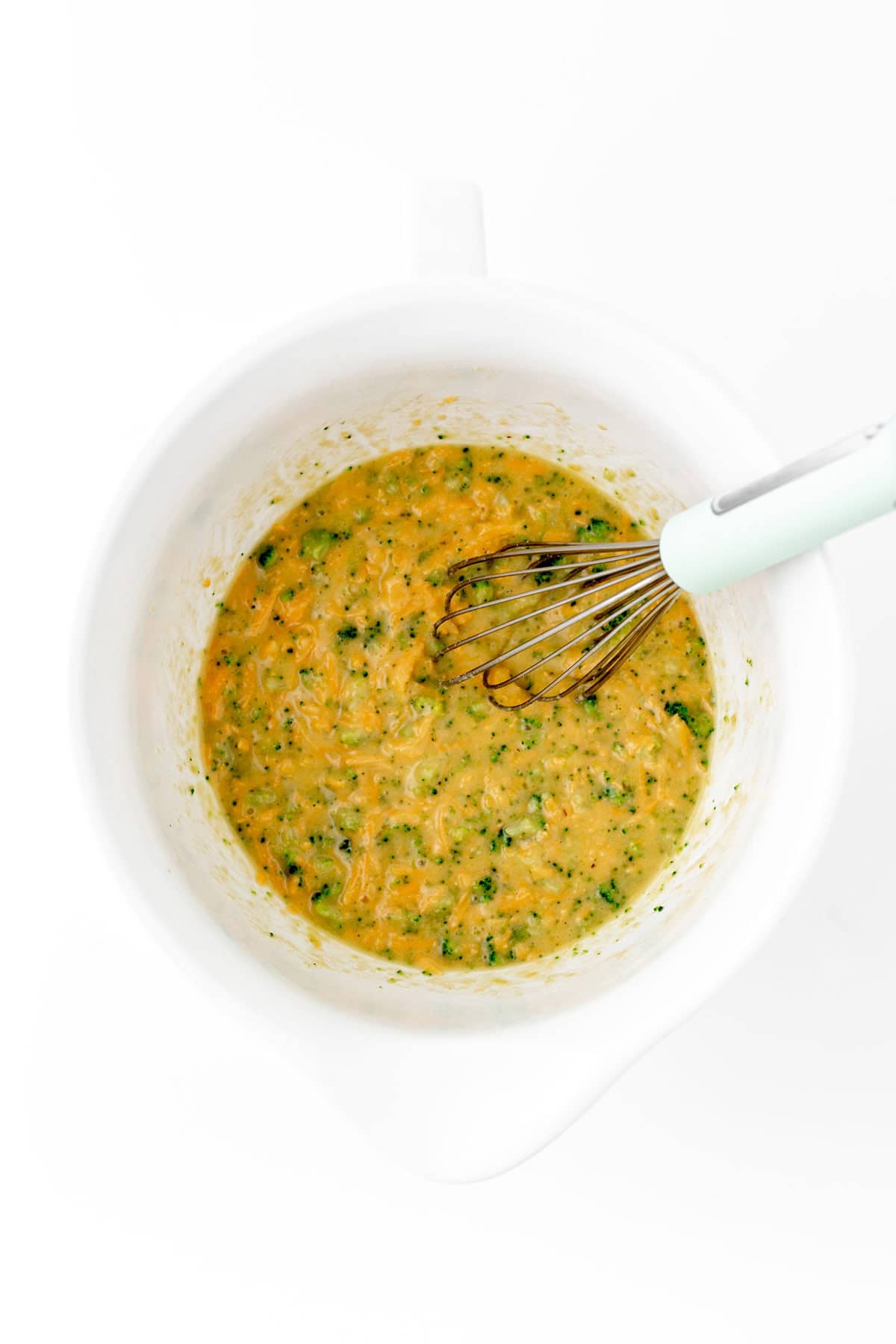 Whisking the broccoli cheese waffle ingredients in a mixing bowl.