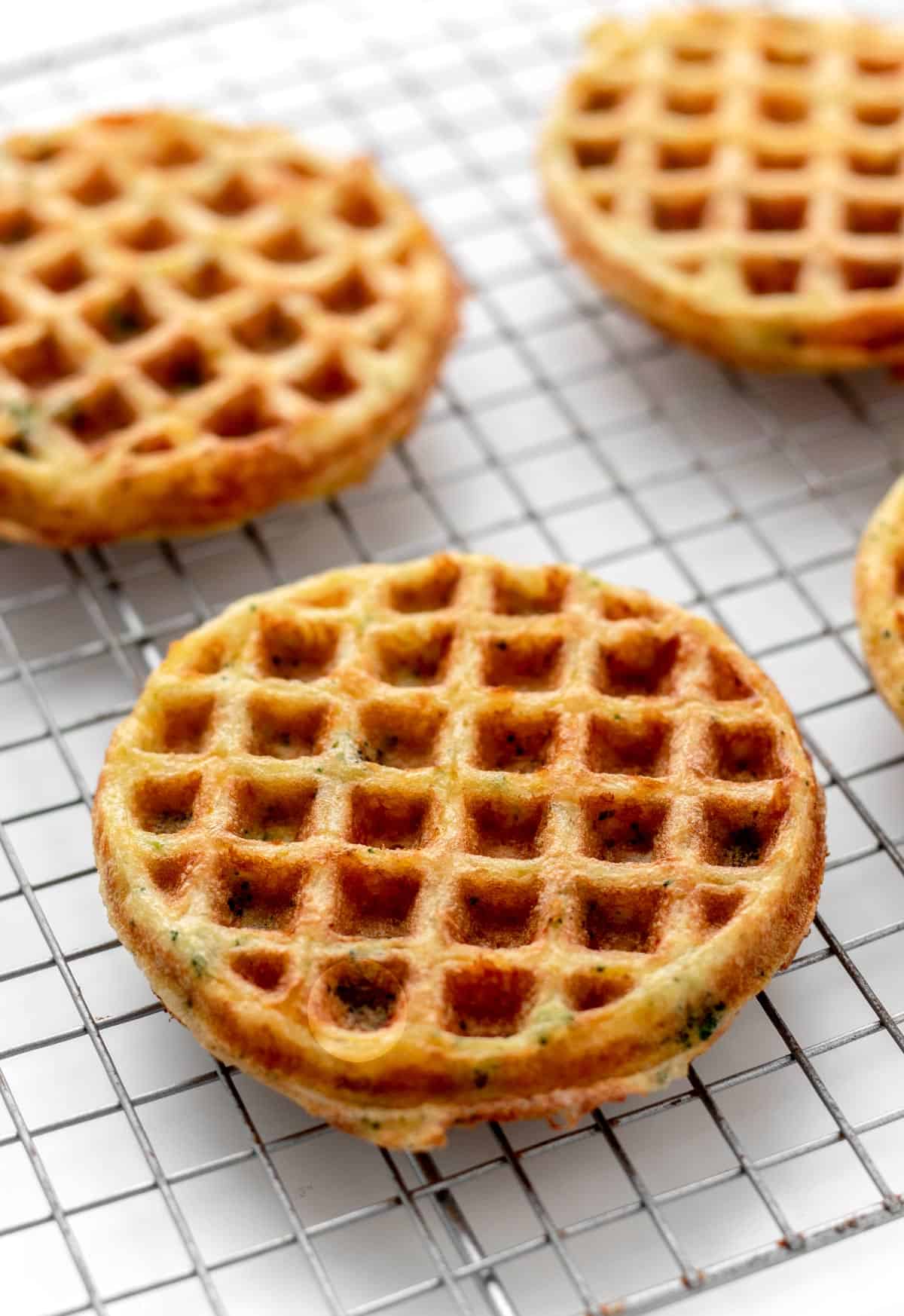 A close-up of broccoli cheese waffles on a cooling rack.