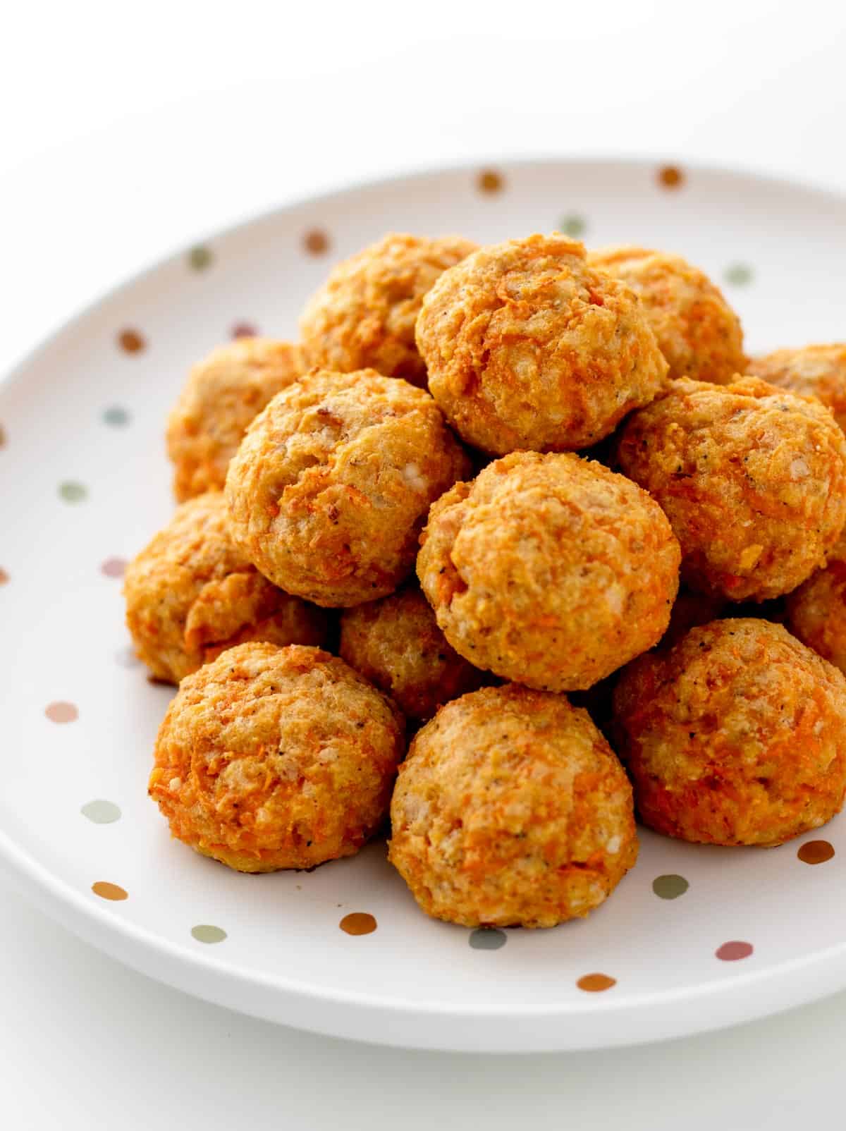 Carrot and cheese bites stacked on a polka dot plate.