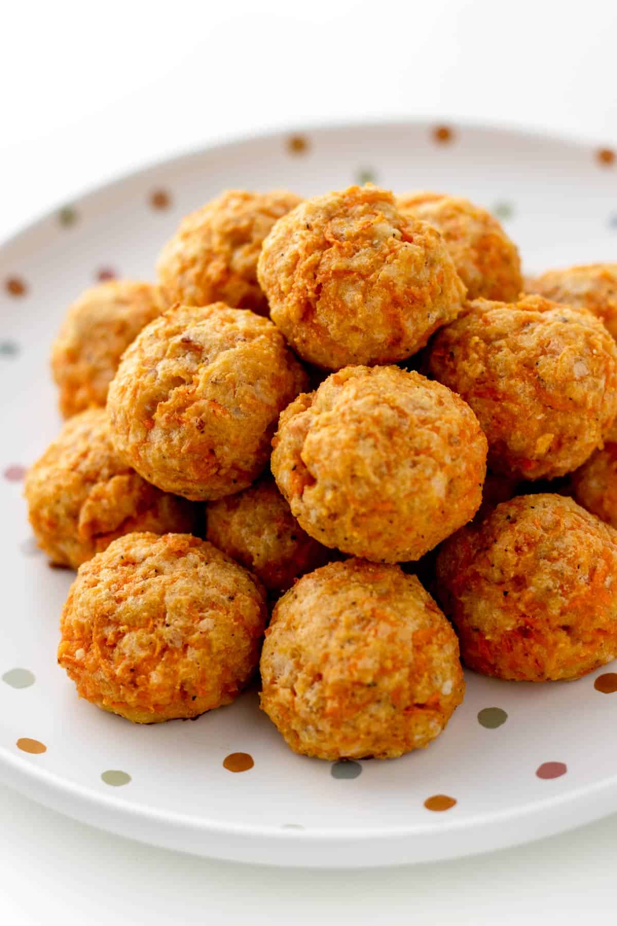 Carrot and cheese bites stacked on top of each other on a polka dot plate.