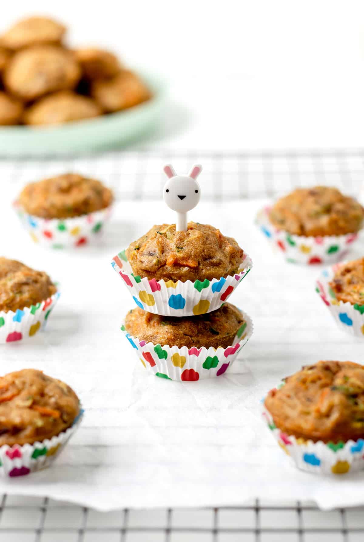 Carrot zucchini banana muffins stacked on top of one another with an animal toothpick going through the top muffin.