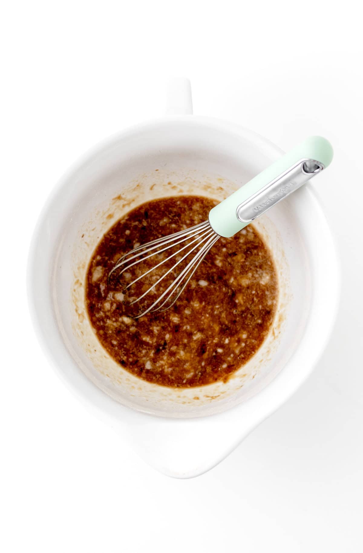 Whisking together the mashed banana, coconut oil, maple syrup, eggs and vanilla in a bowl with a whisk.