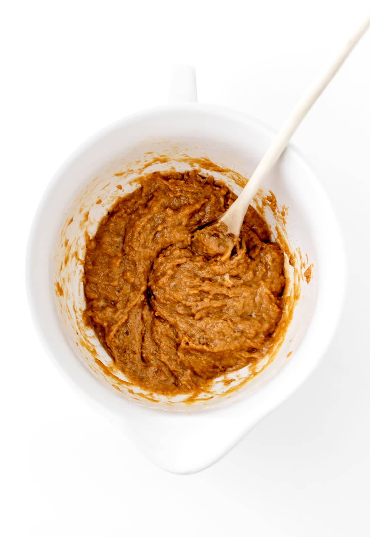 Adding the flour into a bowl with the wet ingredients and stirring with a spoon.