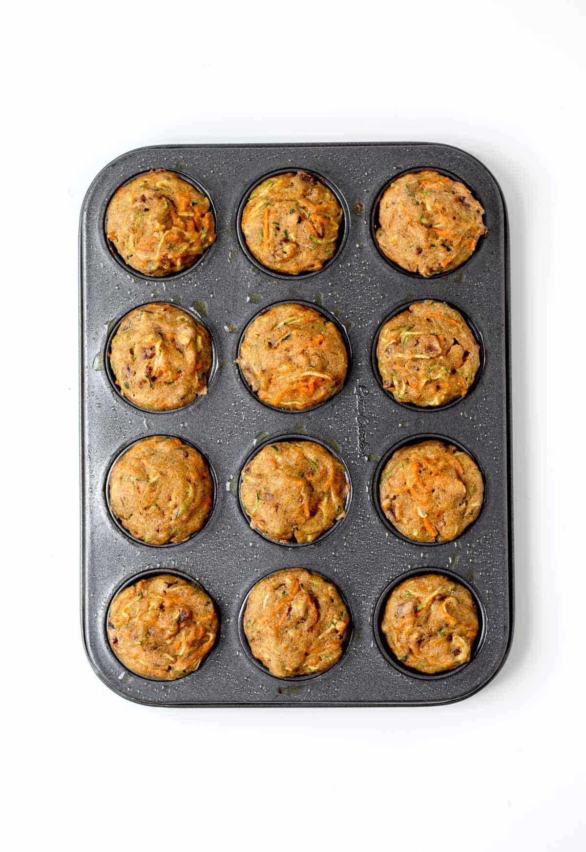 A birds-eye view of zucchini muffins in a muffin pan after baking.