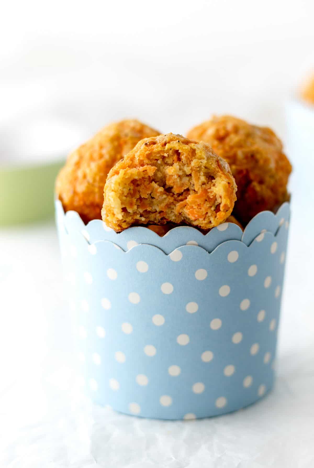 Cheesy carrot bites in a blue and white polka dotted cup.