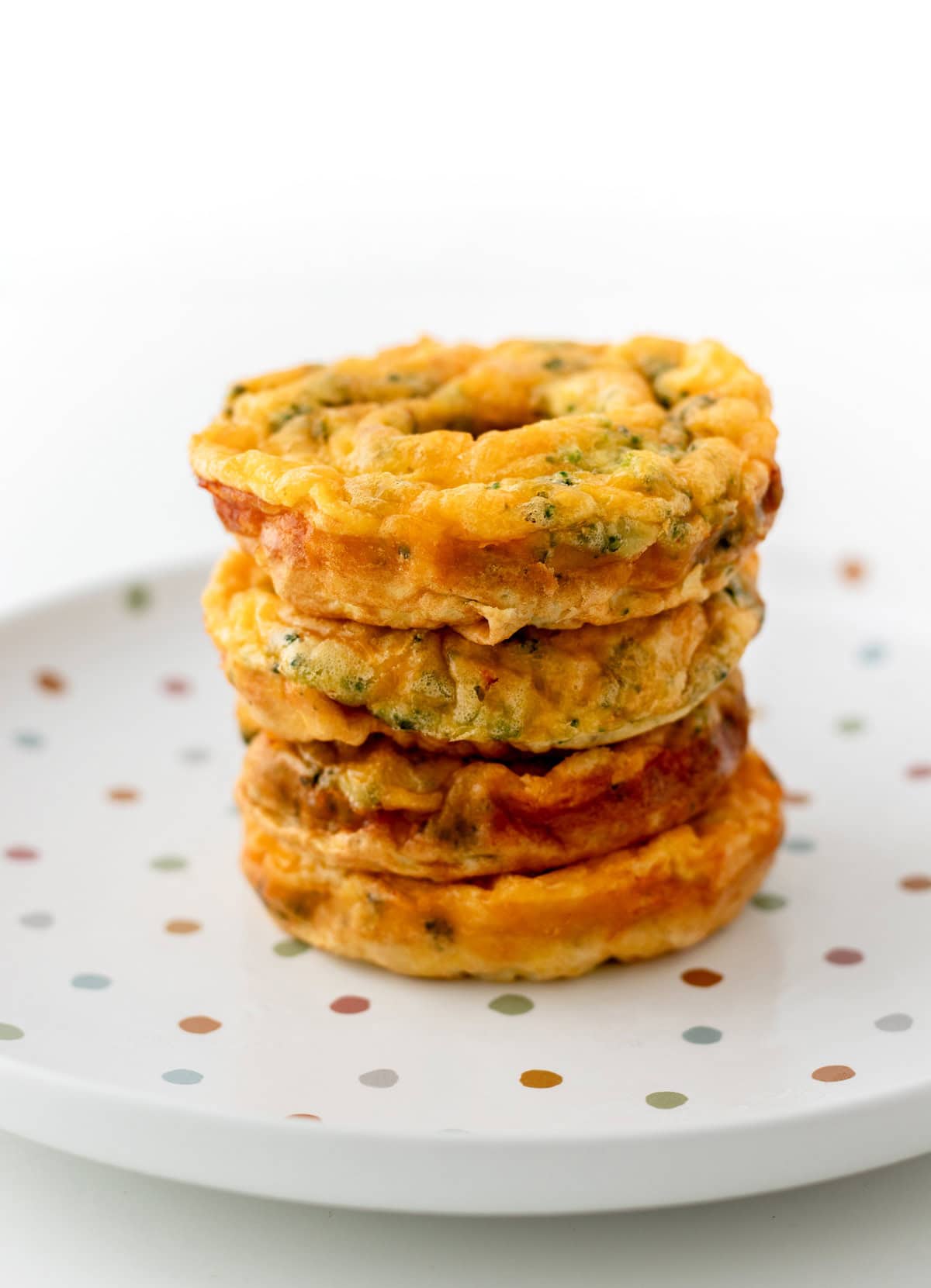 Egg donuts stacked on a colorful polka dot plate.