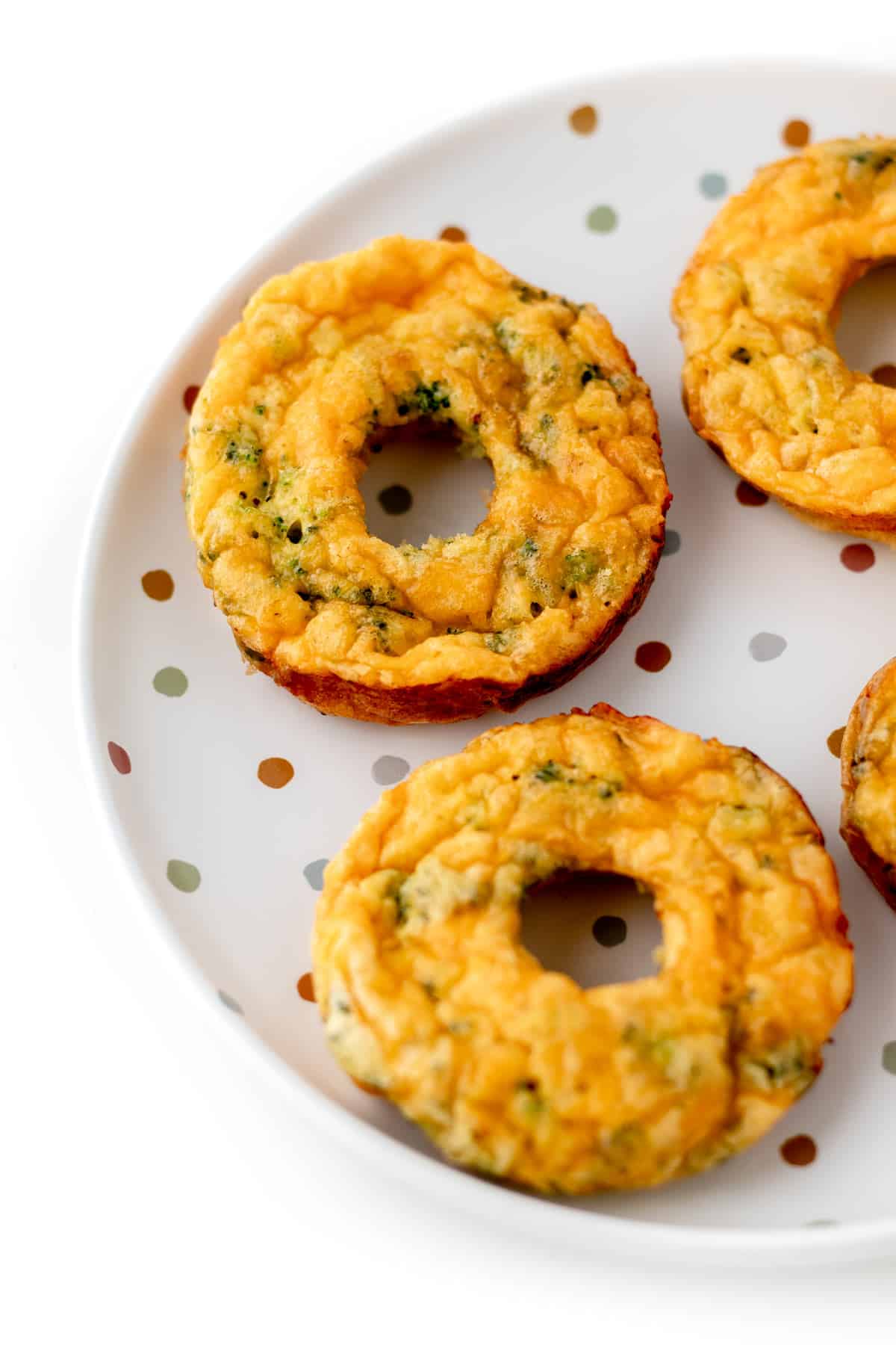 A close-up of broccoli and cheese egg donuts on a plate.