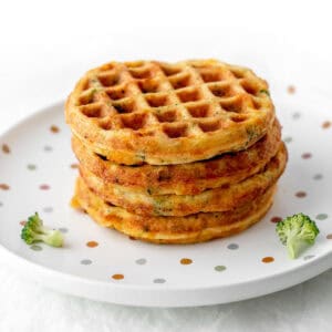 A stack of broccoli cheese waffles on a polka dot plate.