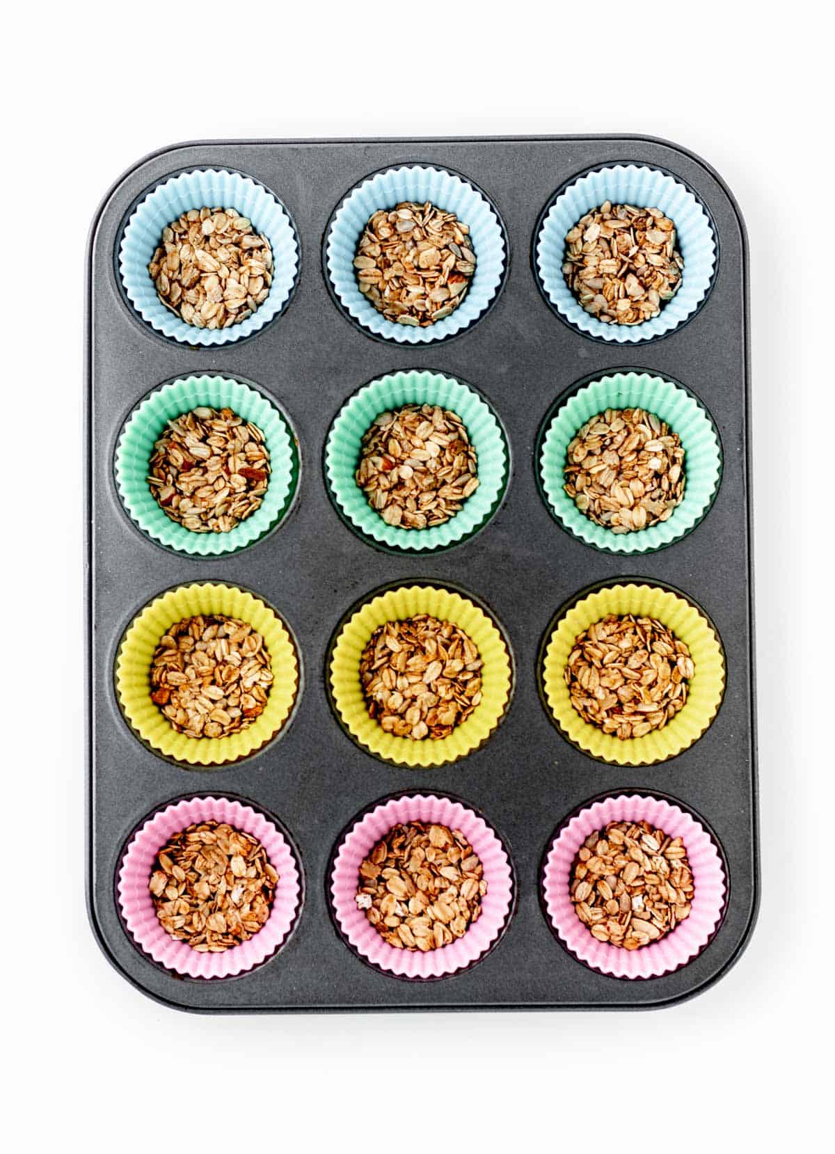 Granola in the bottom of each muffin liner in a muffin pan.